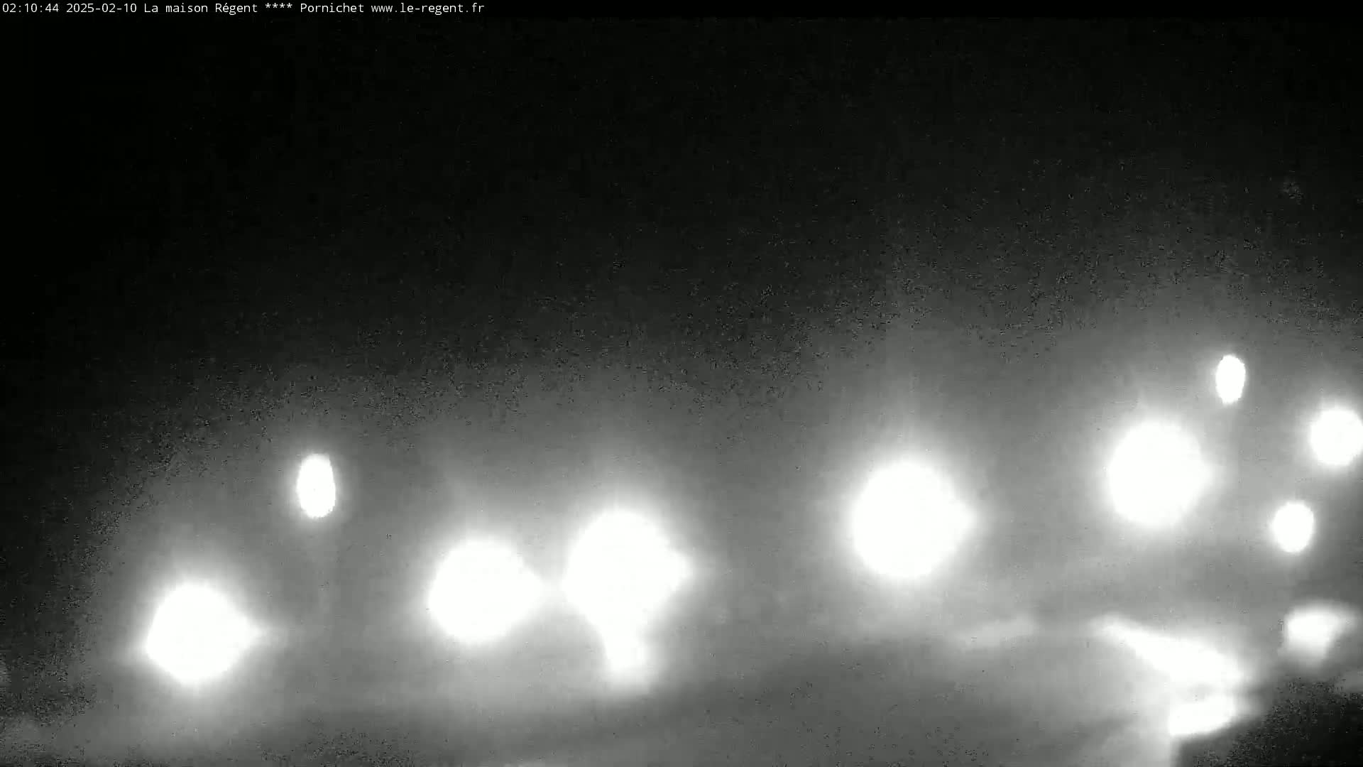 At night, several sets of vehicle headlights are visible through a hazy or foggy atmosphere.