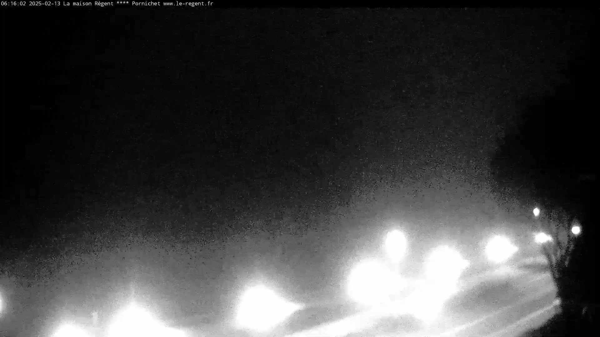 Headlights of vehicles are visible on a foggy, dark night.
