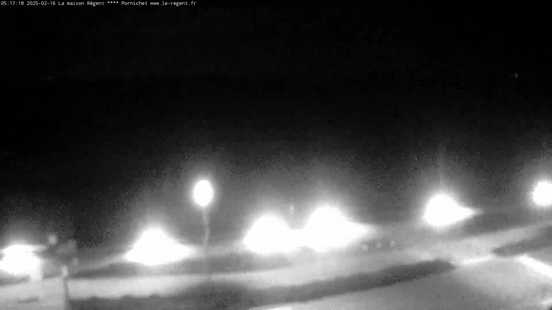 A nighttime, low-light view shows several bright lights illuminating a dark, possibly snowy or icy, ground.