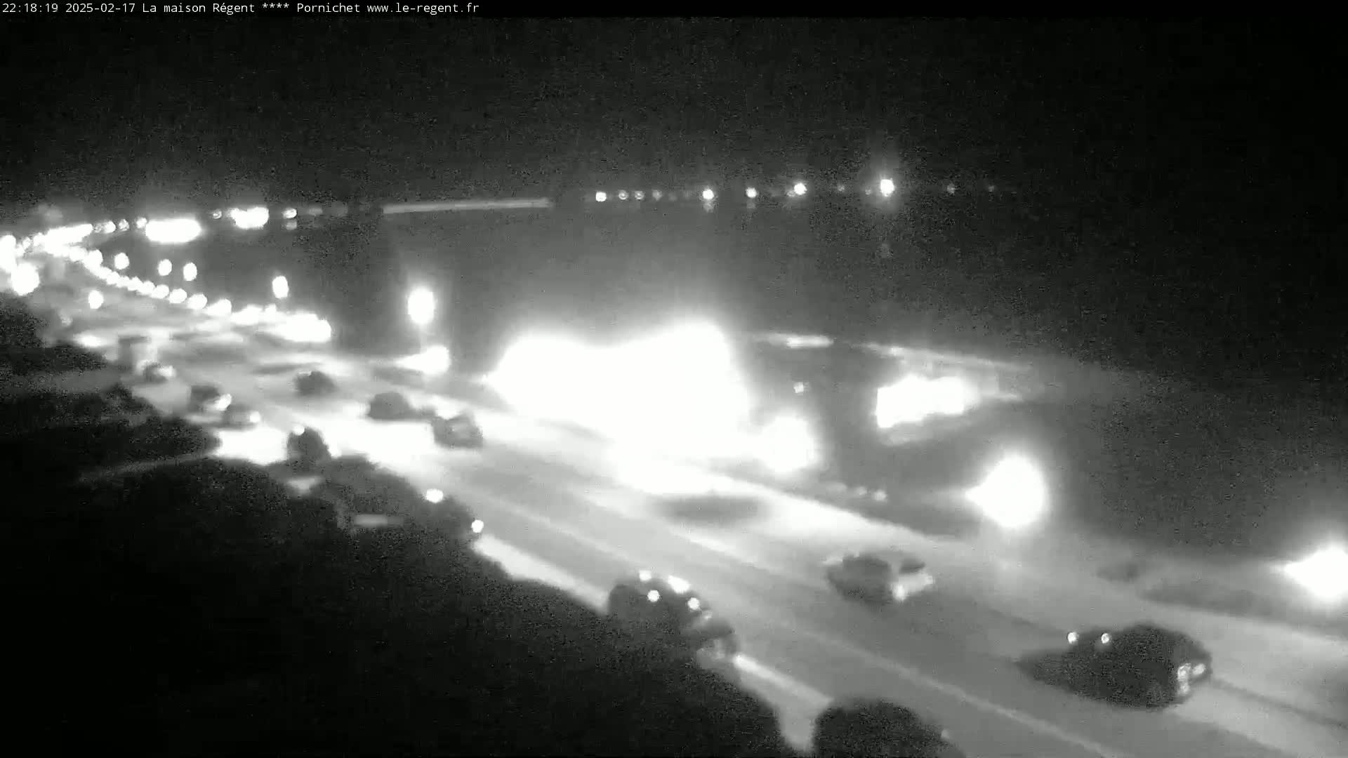 A nighttime highway scene shows multiple vehicles traveling on a snow-covered road under dark conditions.