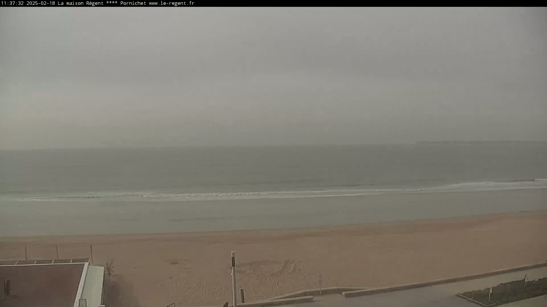 A sandy beach stretches out to a calm, gray ocean under an overcast sky.