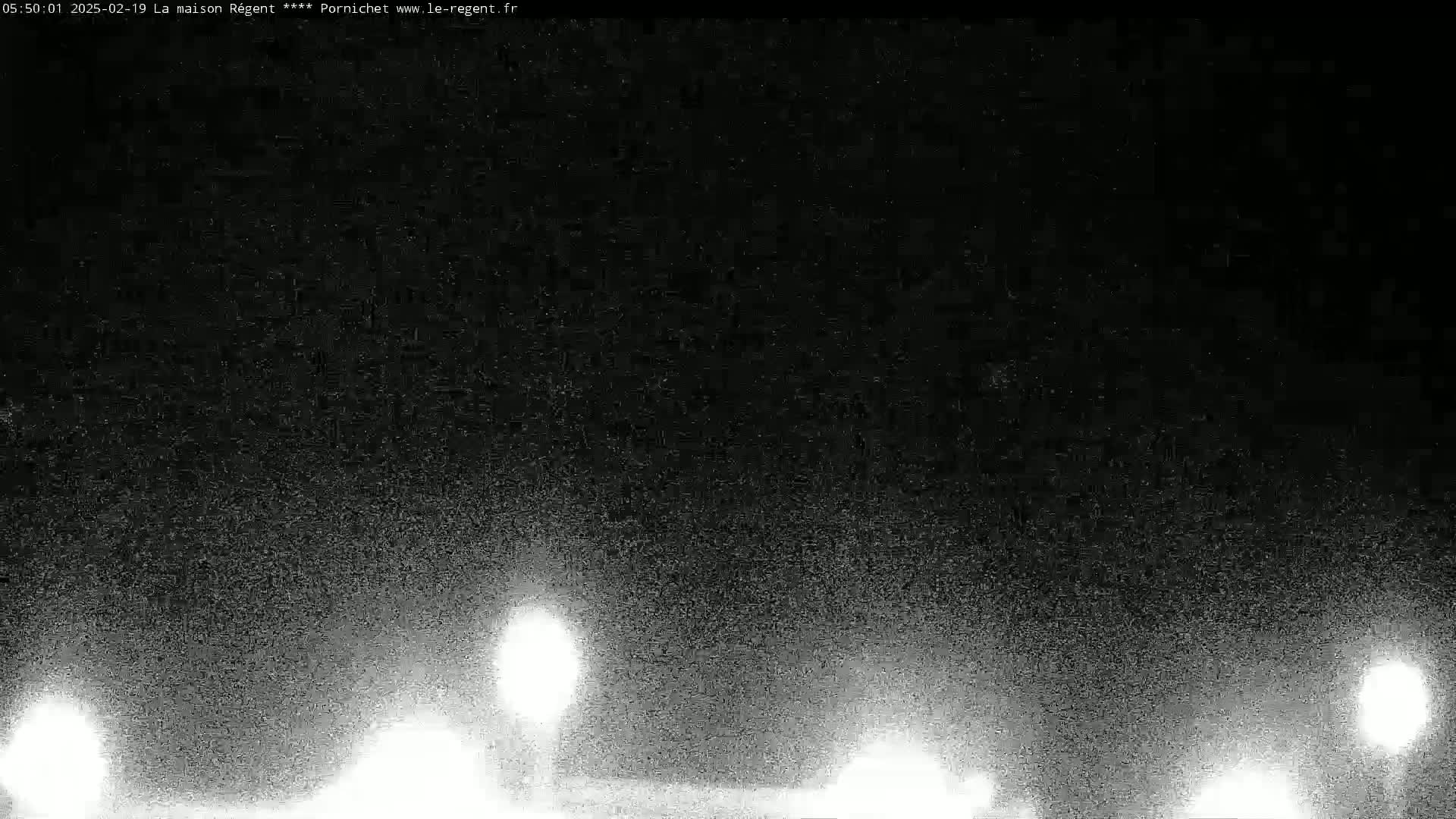 A nighttime, grainy image shows several bright lights in the distance at ground level.
