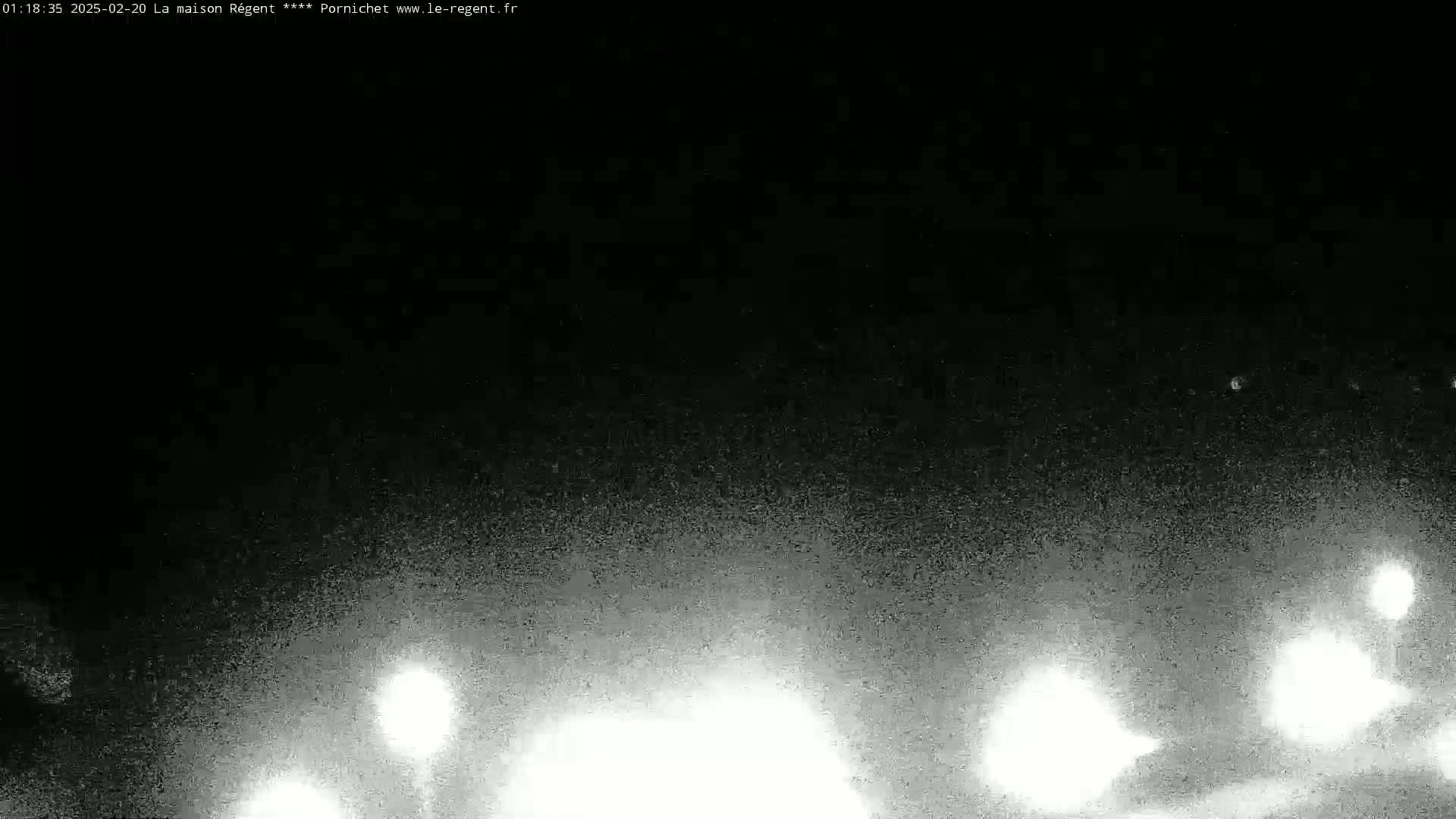 A nighttime, grainy image shows bright lights in the lower third of the frame against a dark, possibly snowy or hazy sky.