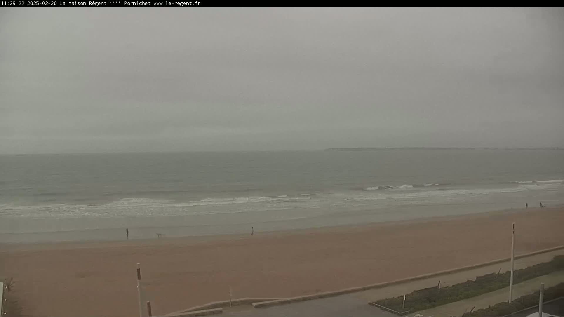 A wide shot of a beach with small waves on an overcast day.