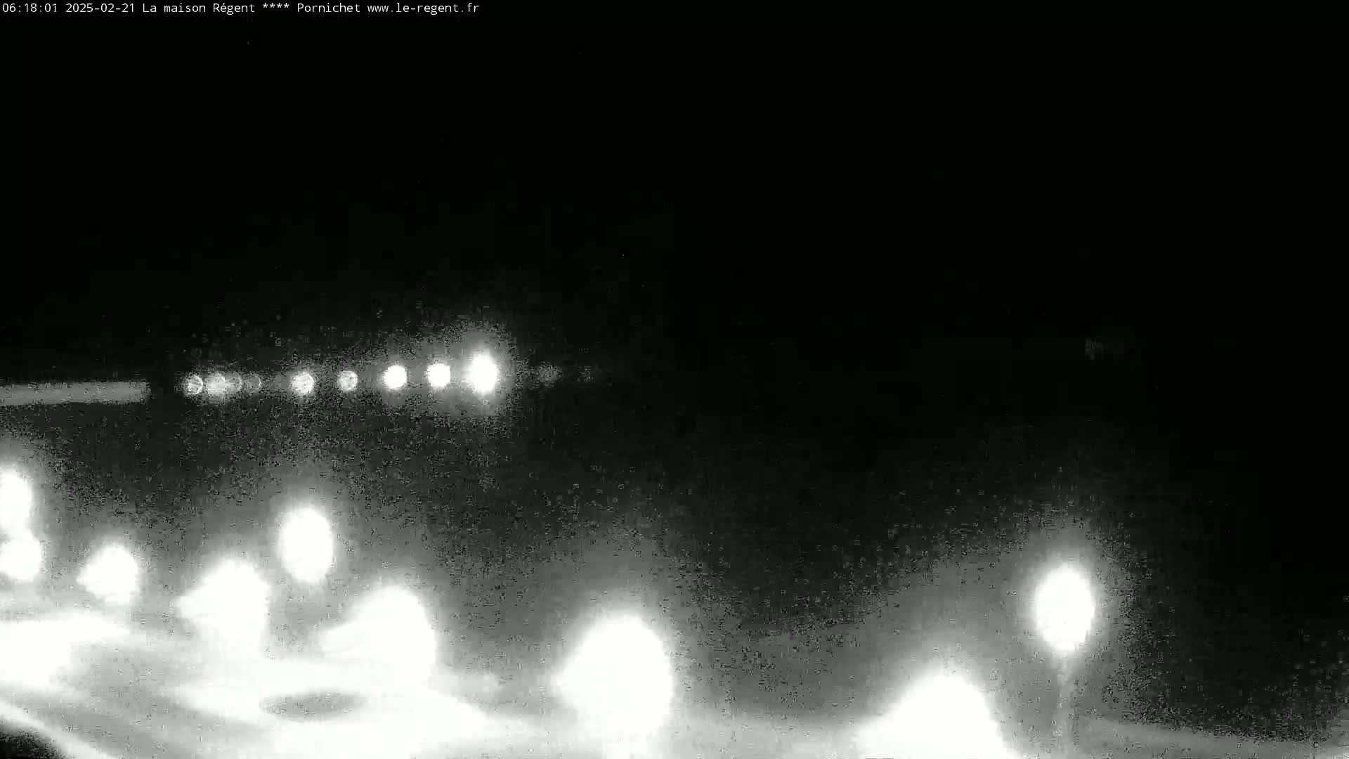 A nighttime, low-visibility view of a road with blurry lights from vehicles and streetlights.