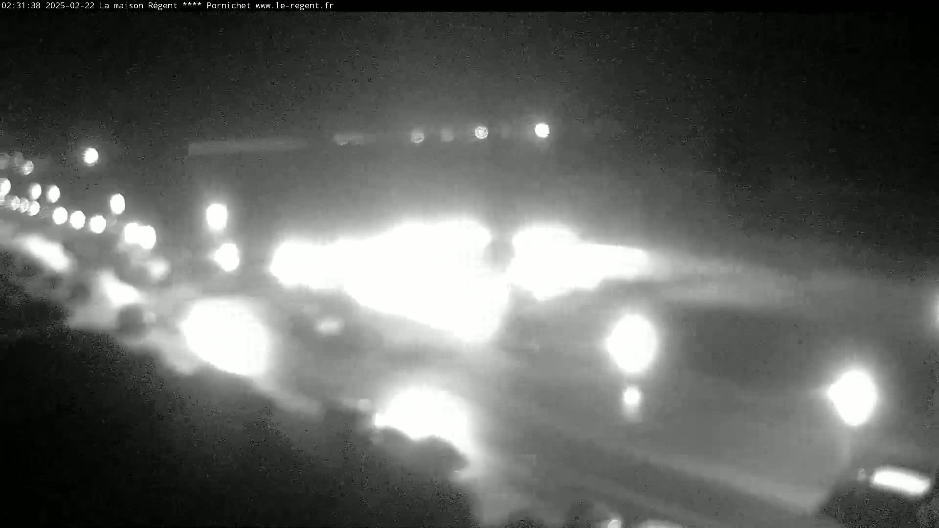 A nighttime, blurry view of a highway with many cars driving, their headlights creating streaks of light.