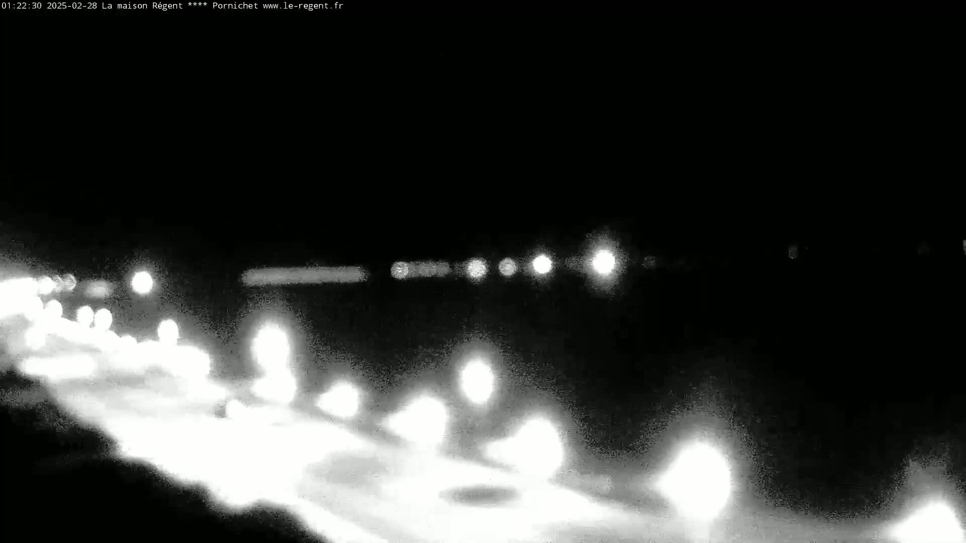 A nighttime, blurry view of a road with headlights from several vehicles traveling in both directions.