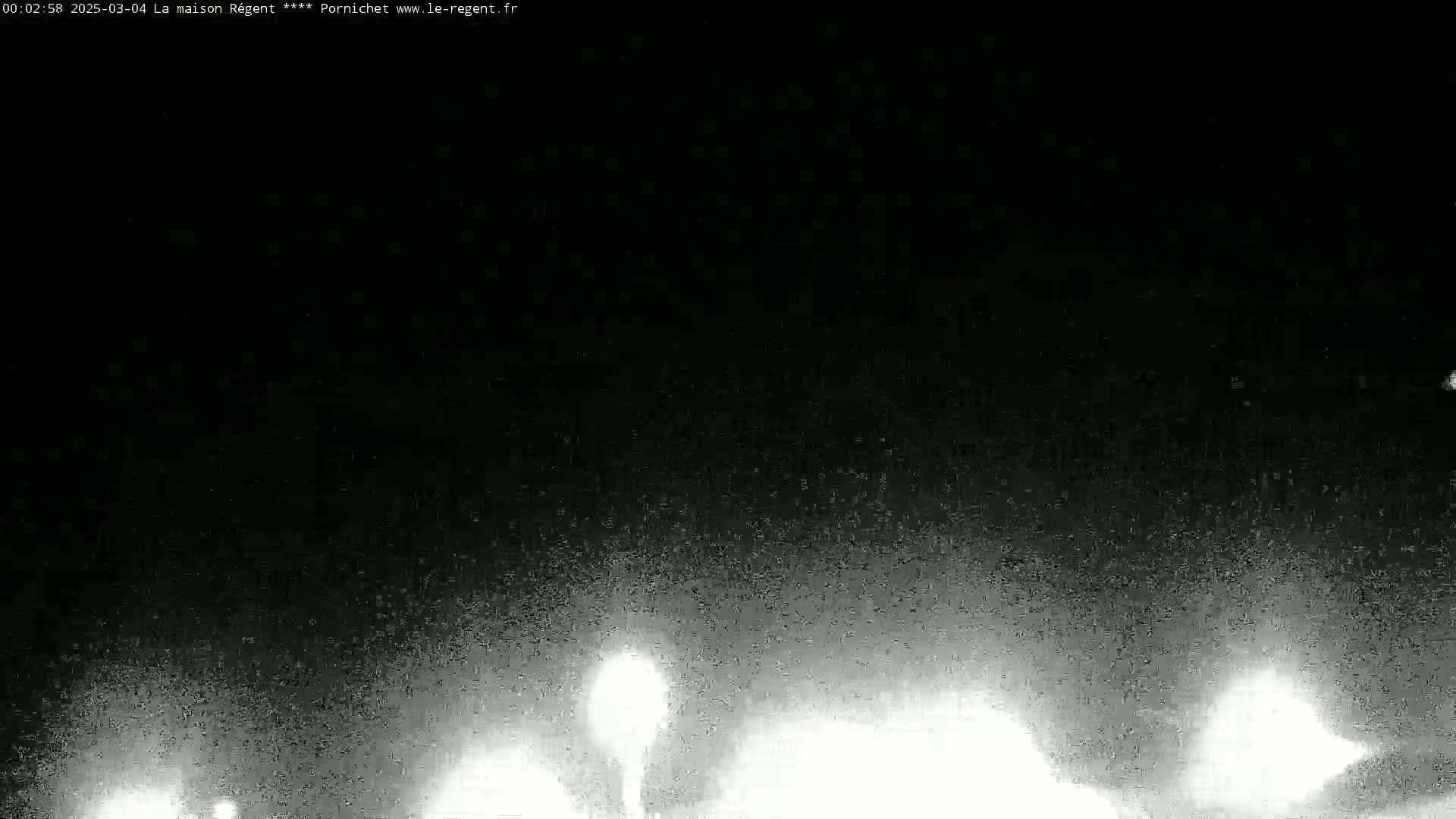 A nighttime, low-light image shows bright, blurry lights in the lower portion of the frame against a dark, grainy background.