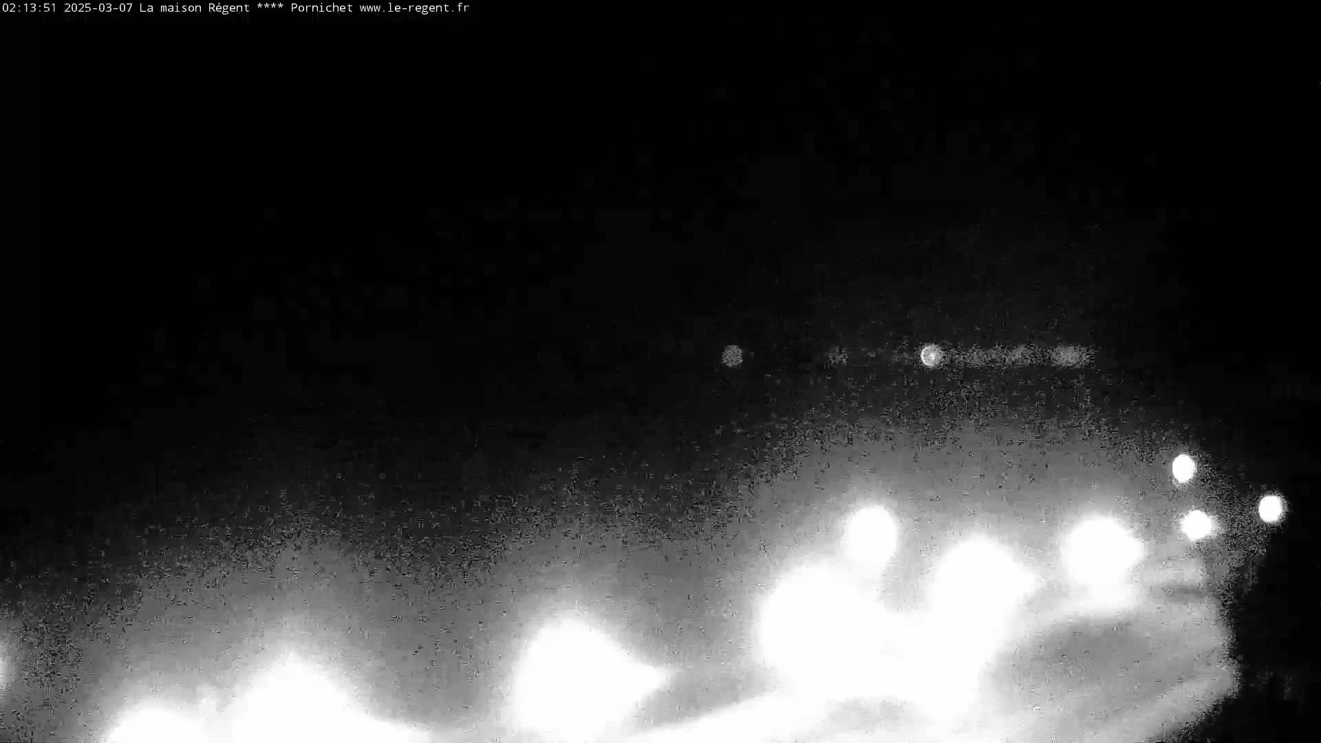 At night, blurry white lights from vehicles are visible in the distance through a hazy or snowy atmosphere.