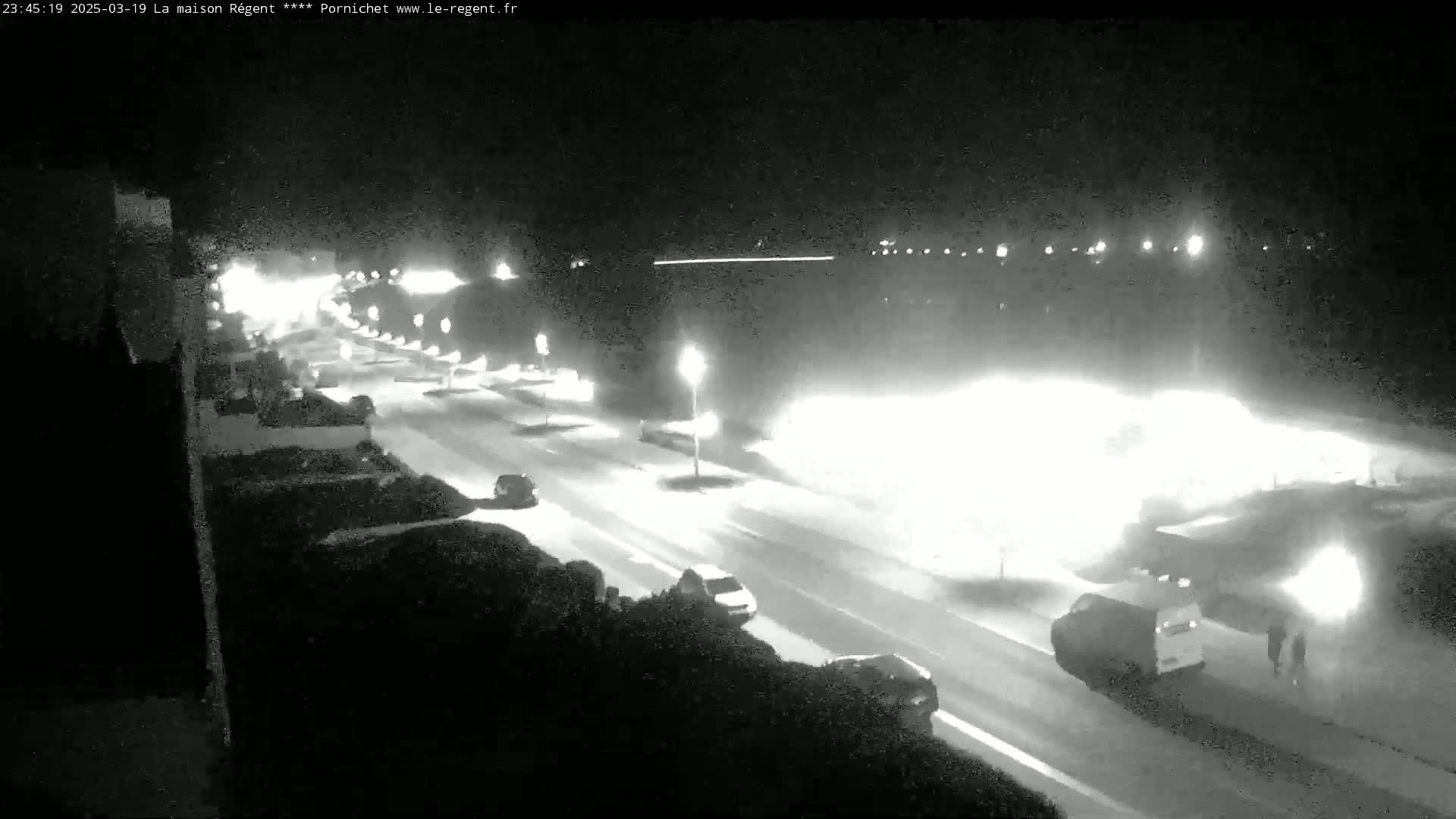 A snow-covered road at night is illuminated by streetlights and headlights of vehicles driving in both directions.