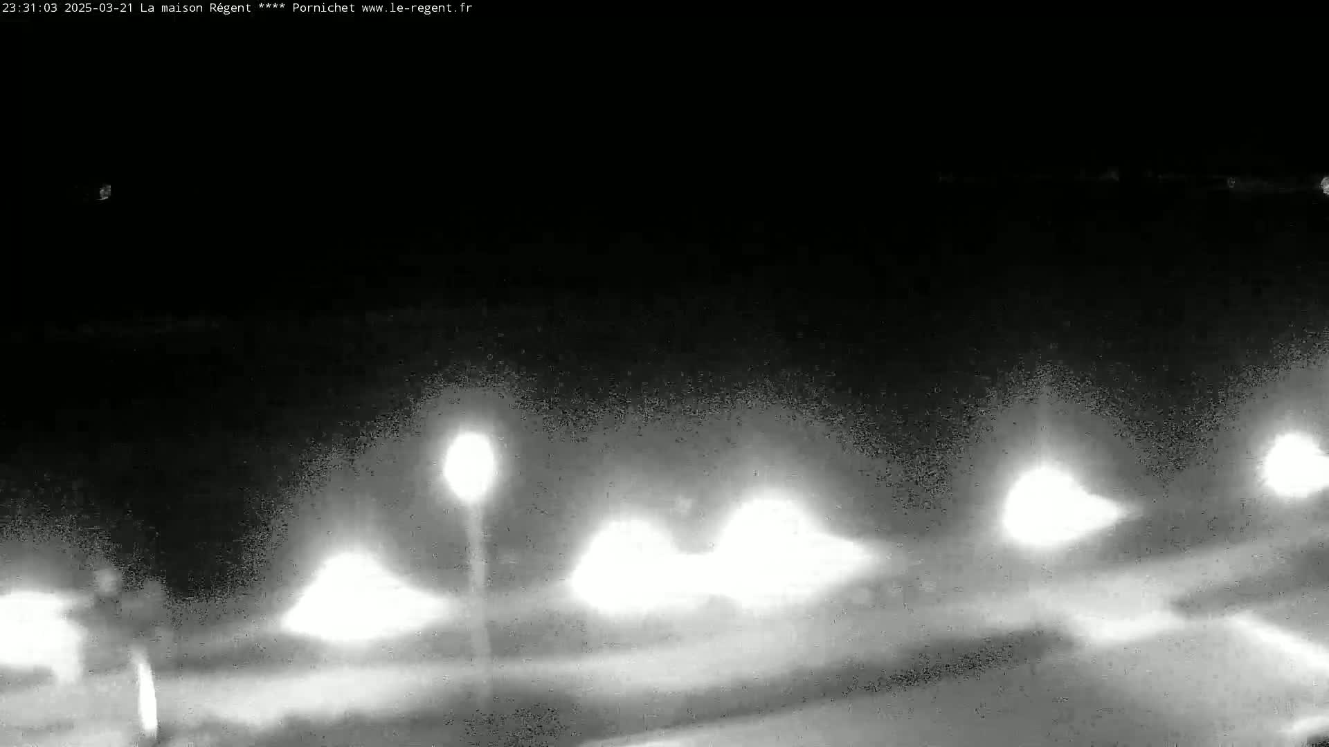 A nighttime, blurry, low-light view shows several bright lights at a distance, possibly from street lamps or vehicles.