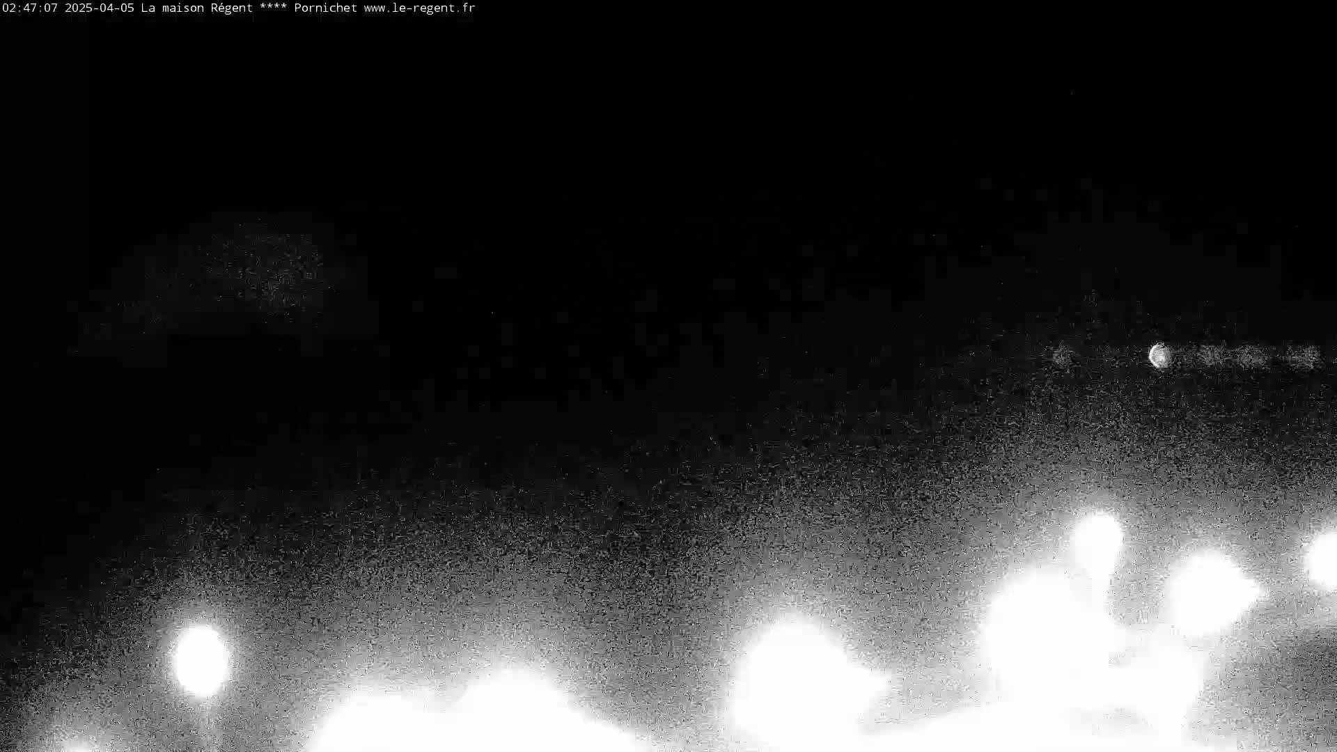 A nighttime, low-light outdoor scene shows bright lights at the bottom and fainter lights in the sky.