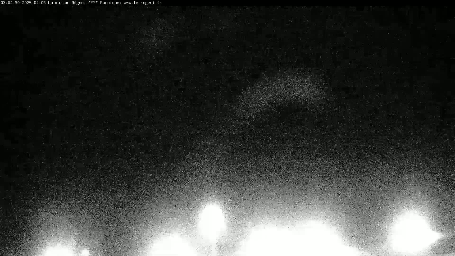 A grainy, nighttime image shows bright lights at the bottom, possibly from cars' headlights, against a dark sky.