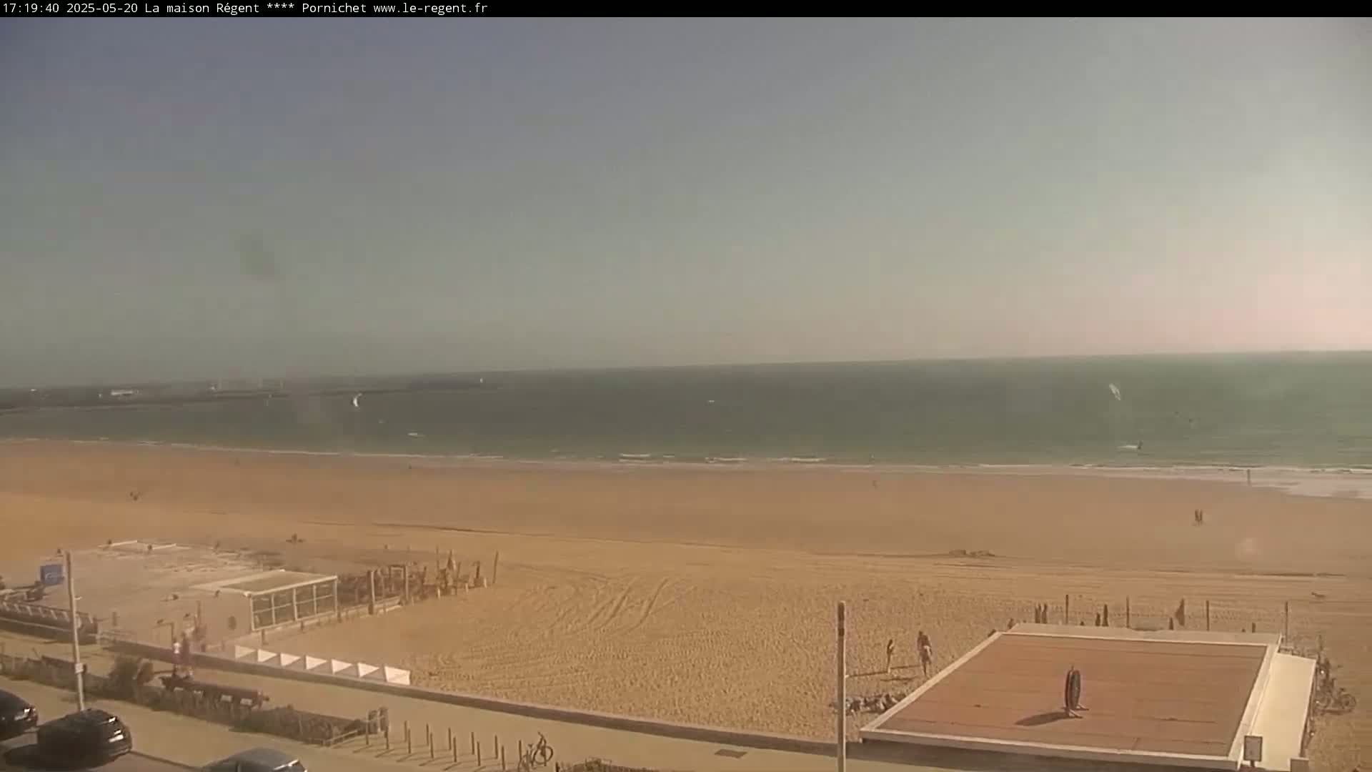 A sandy beach stretches to a calm ocean under a clear, bright sky.