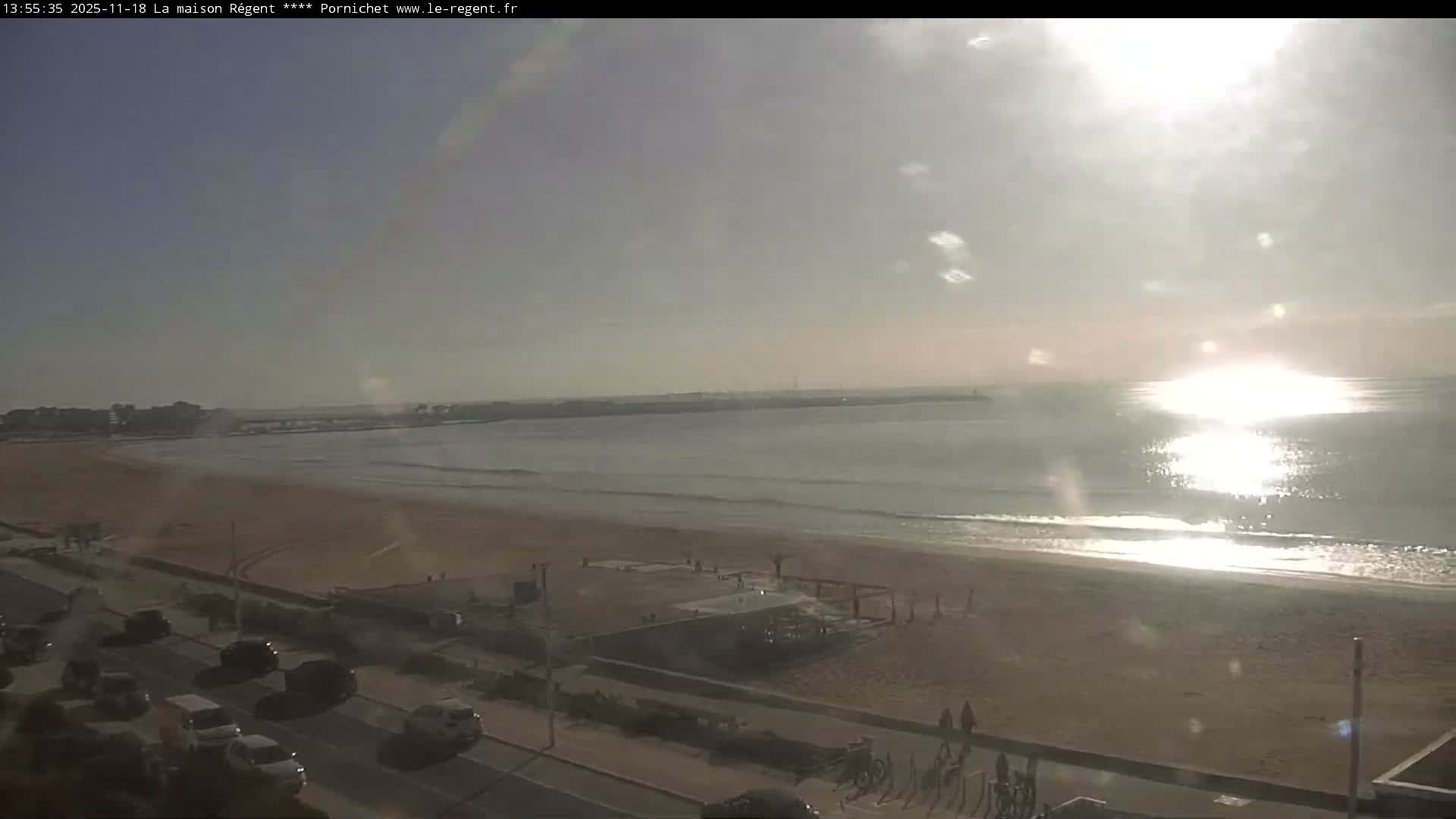 A nighttime, low-light view shows a road with headlights from approaching vehicles and streetlights visible in the distance under a dark sky.