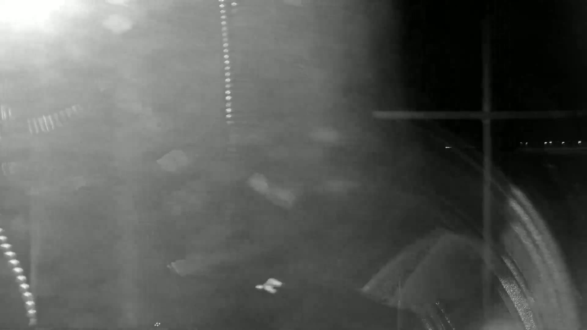 A blurry, nighttime image shows a vehicle's interior with snow or rain obscuring the view outside.