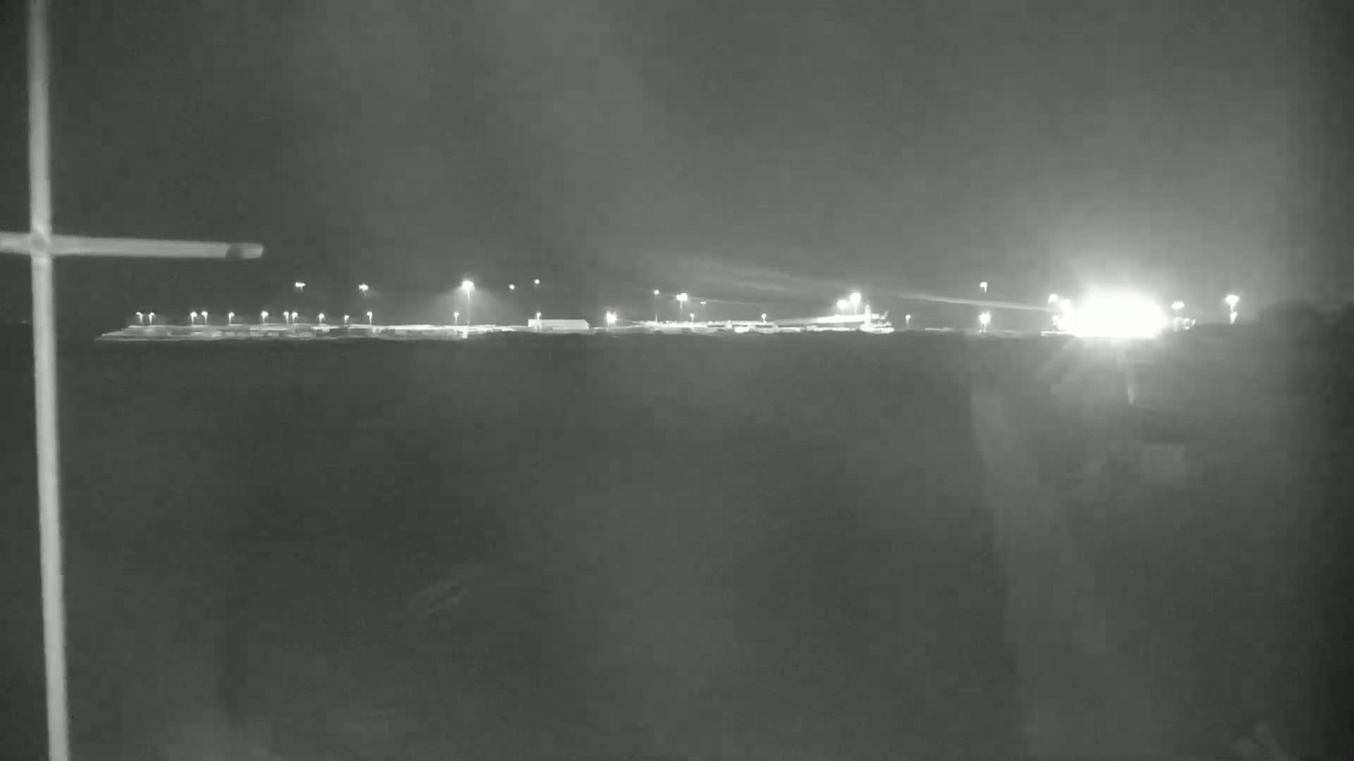 A nighttime, low-light view of a brightly lit industrial area or airport.