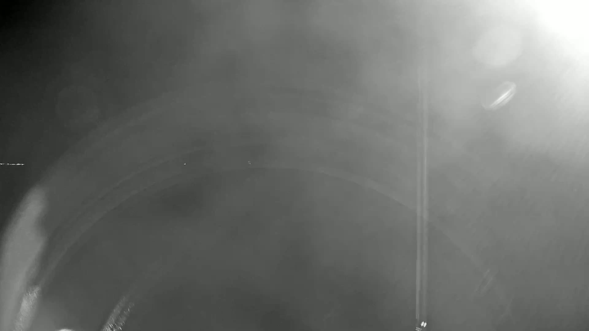 A blurry, grayscale image shows a hazy, possibly foggy, scene with a curved, dark shape dominating the center.