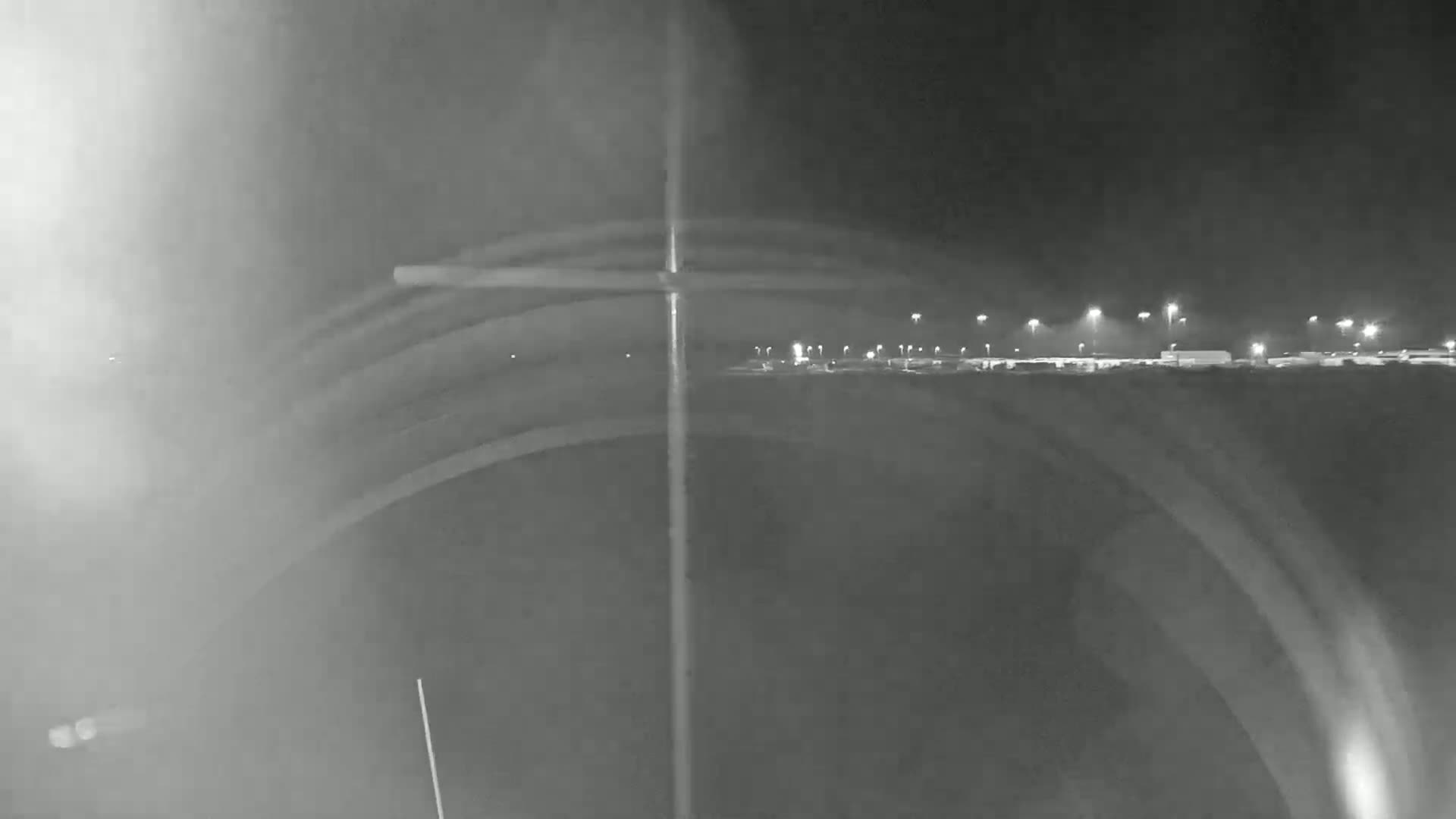 A nighttime view shows a blurry, illuminated roadway and distant buildings through a hazy, possibly foggy, atmosphere.