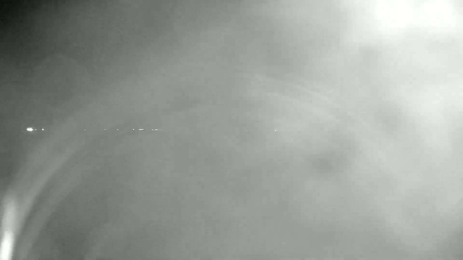 A hazy, nighttime scene shows a line of distant lights obscured by heavy fog or mist.