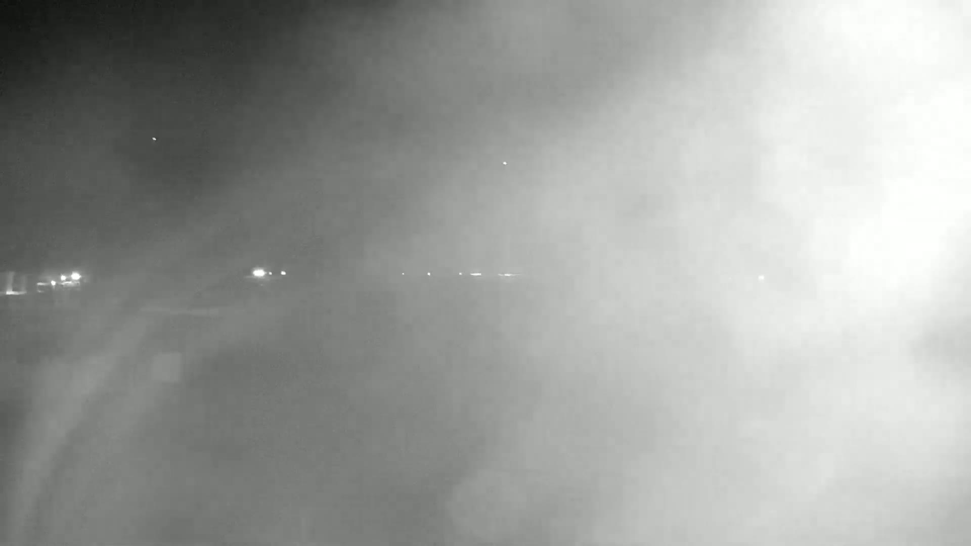 A nighttime scene shows a hazy, foggy landscape with faint lights in the distance.