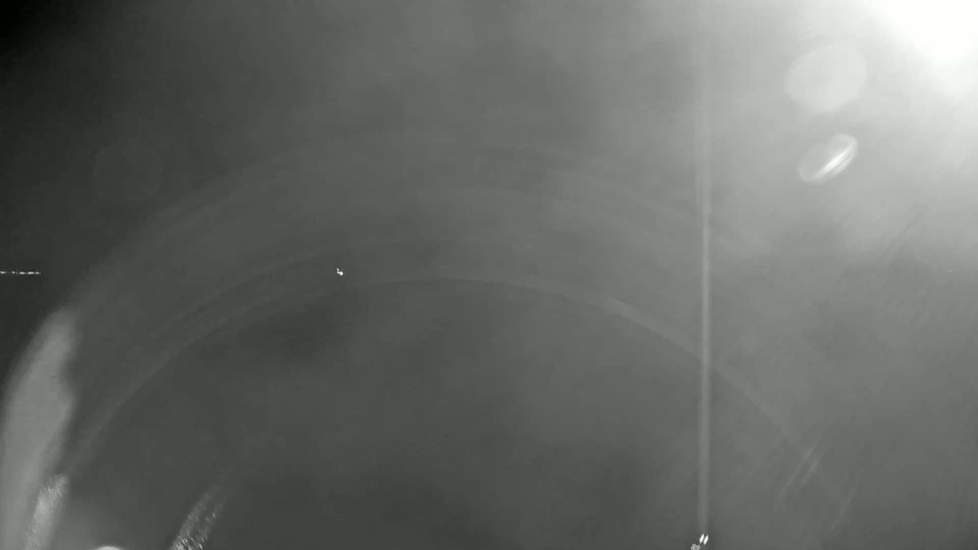 A blurry, grayscale image shows a dark, possibly foggy or smoky, interior space with a curved ceiling.