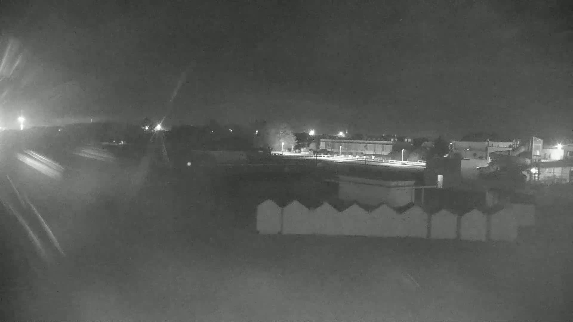 A nighttime view of a roadway and a building complex under a dark sky.