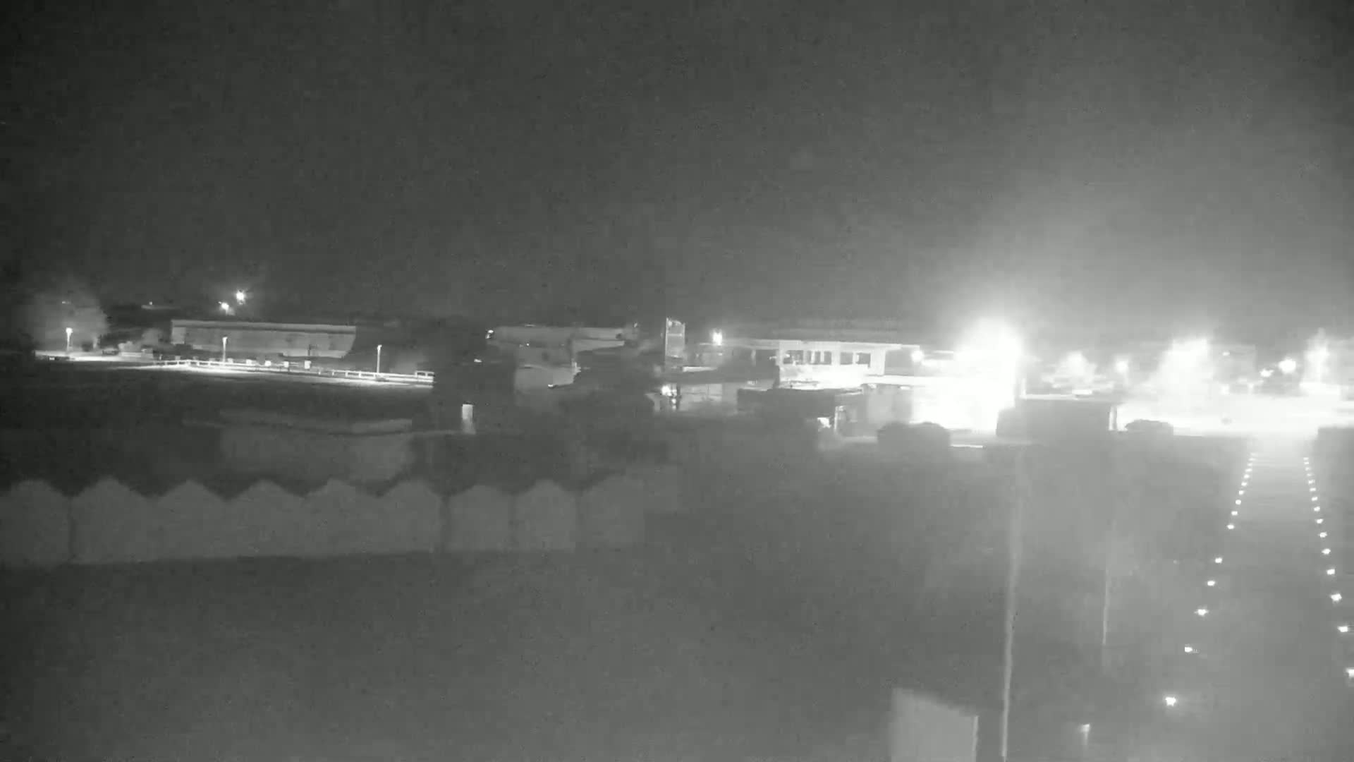 A nighttime, low-light view of a building complex and a roadway with illuminated markings.
