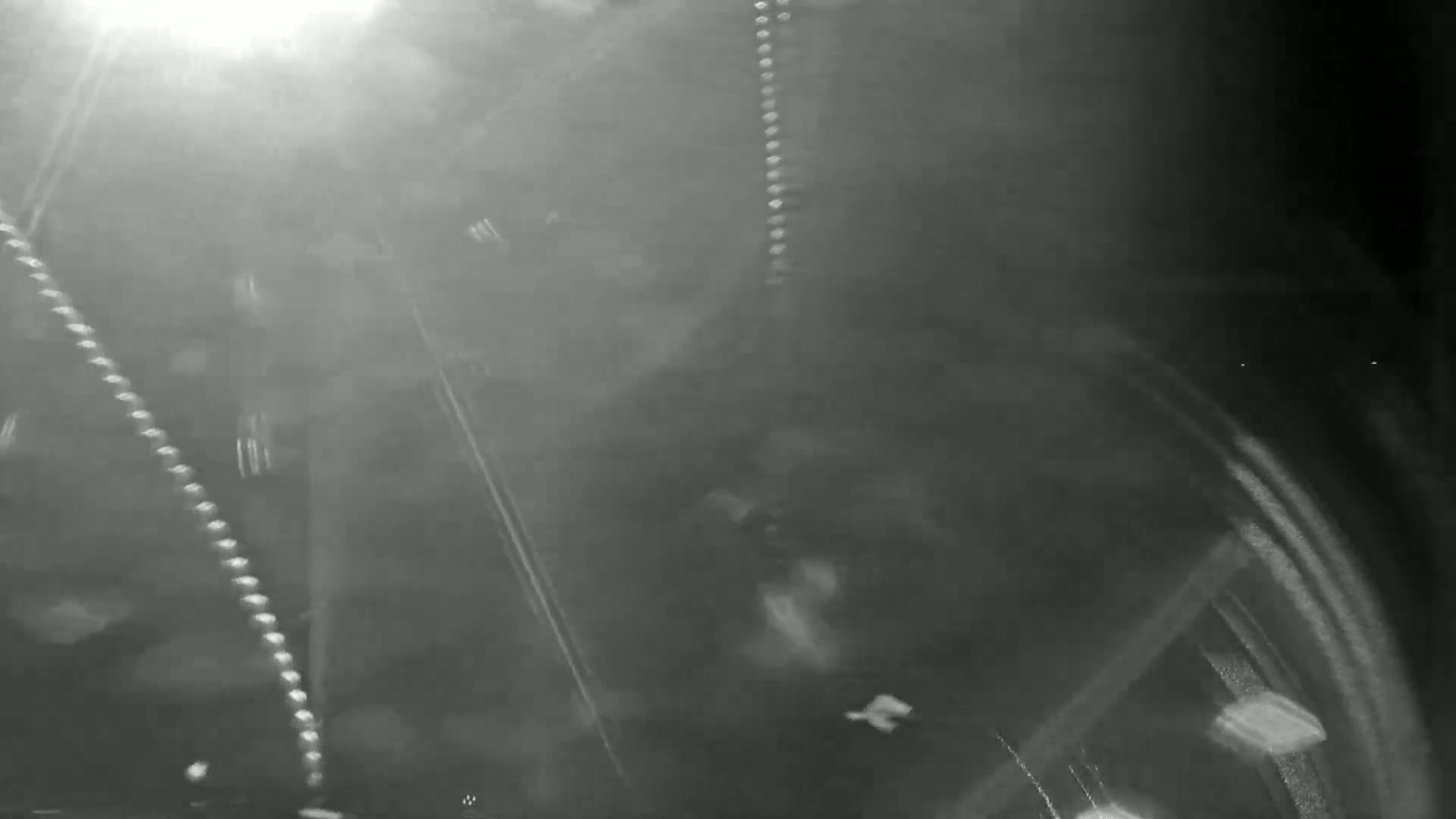 A blurry, dark grayscale image shows light streaks and indistinct shapes suggesting nighttime movement in foggy or snowy conditions.