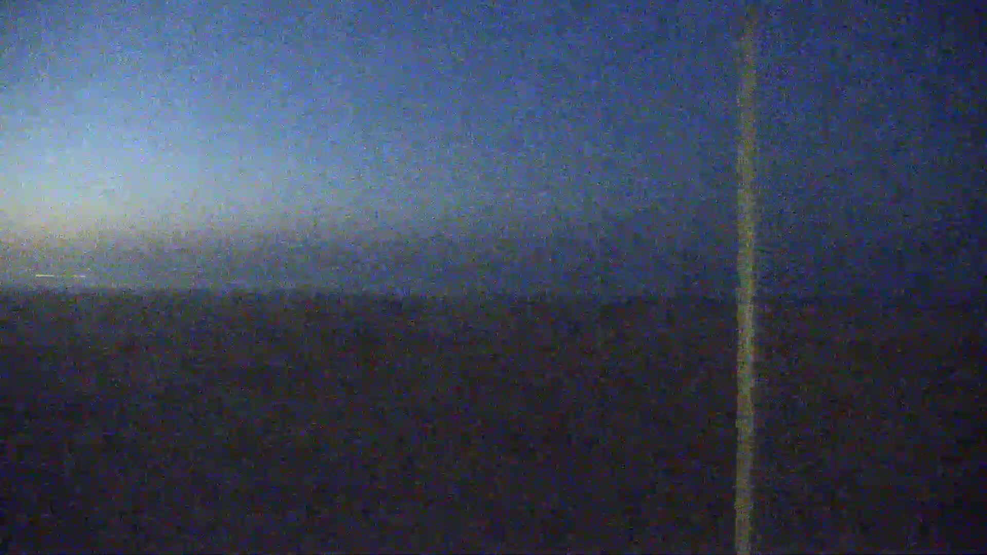 A dark, blurry image shows a flat, dark landscape under a twilight sky.