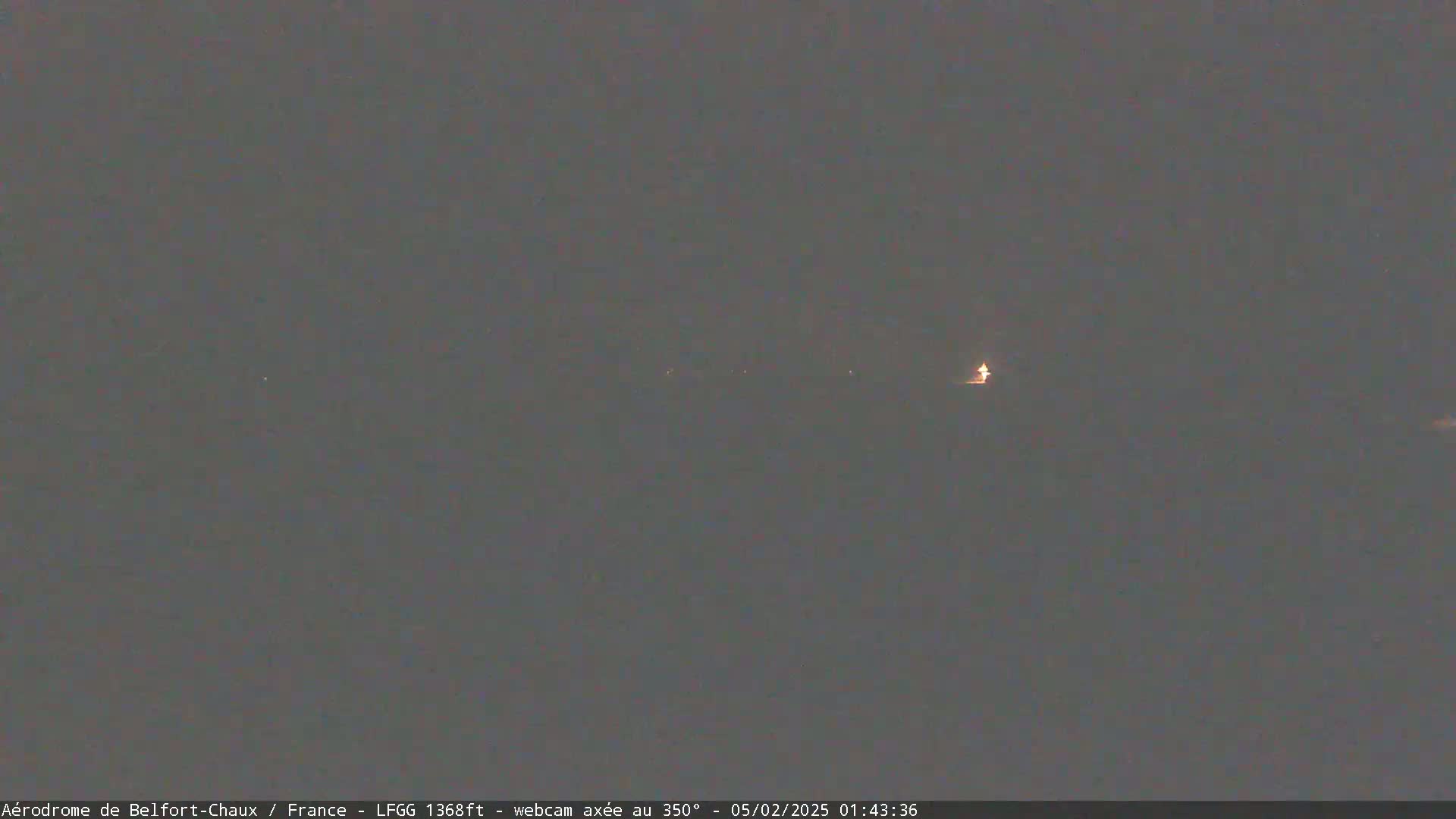 A dimly lit, dark gray nighttime scene shows a few faint lights in the distance.