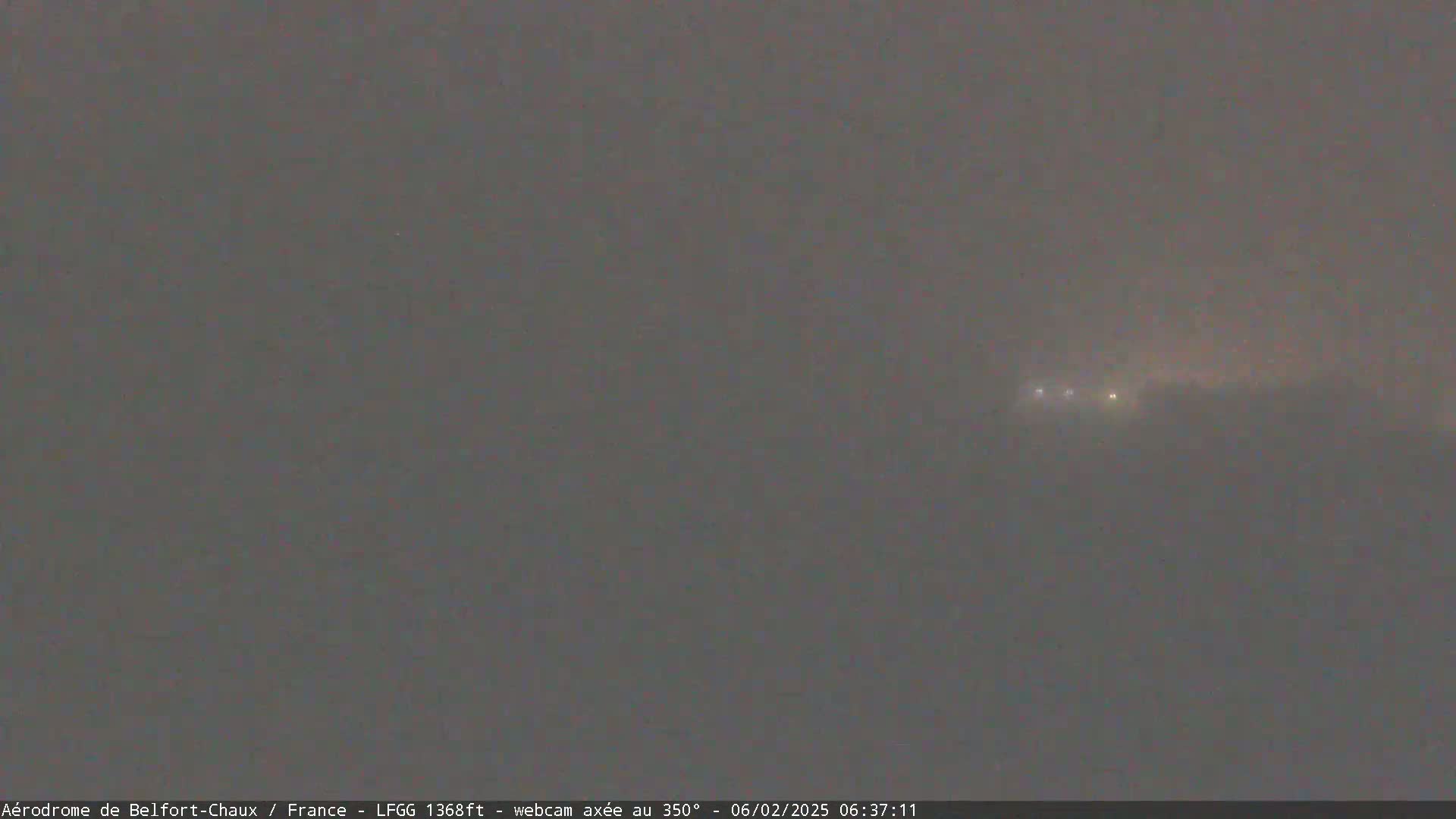A foggy landscape is visible at night, with a few distant lights faintly illuminating the scene.