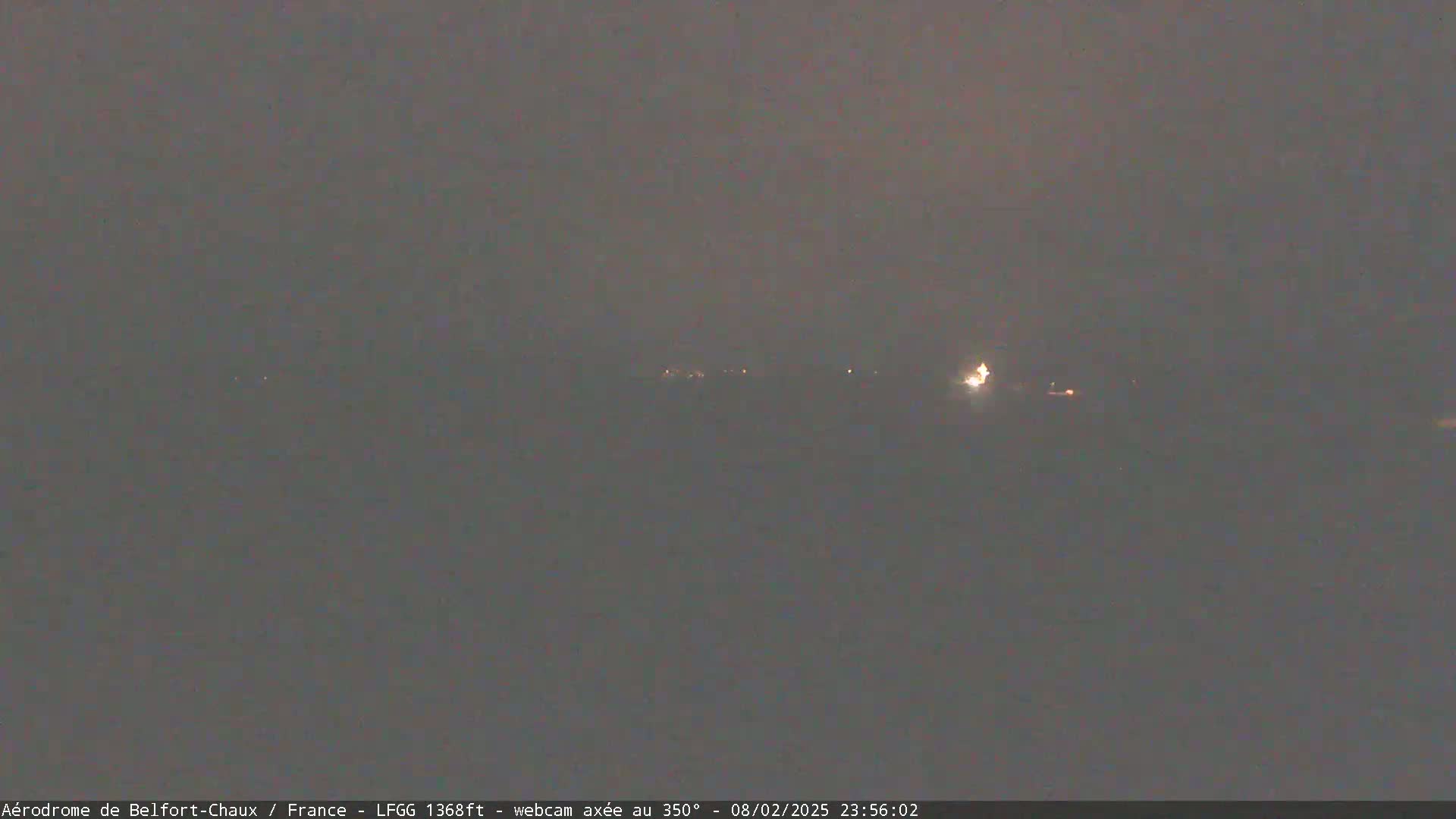 A hazy, dark night scene shows a distant line of faint lights.