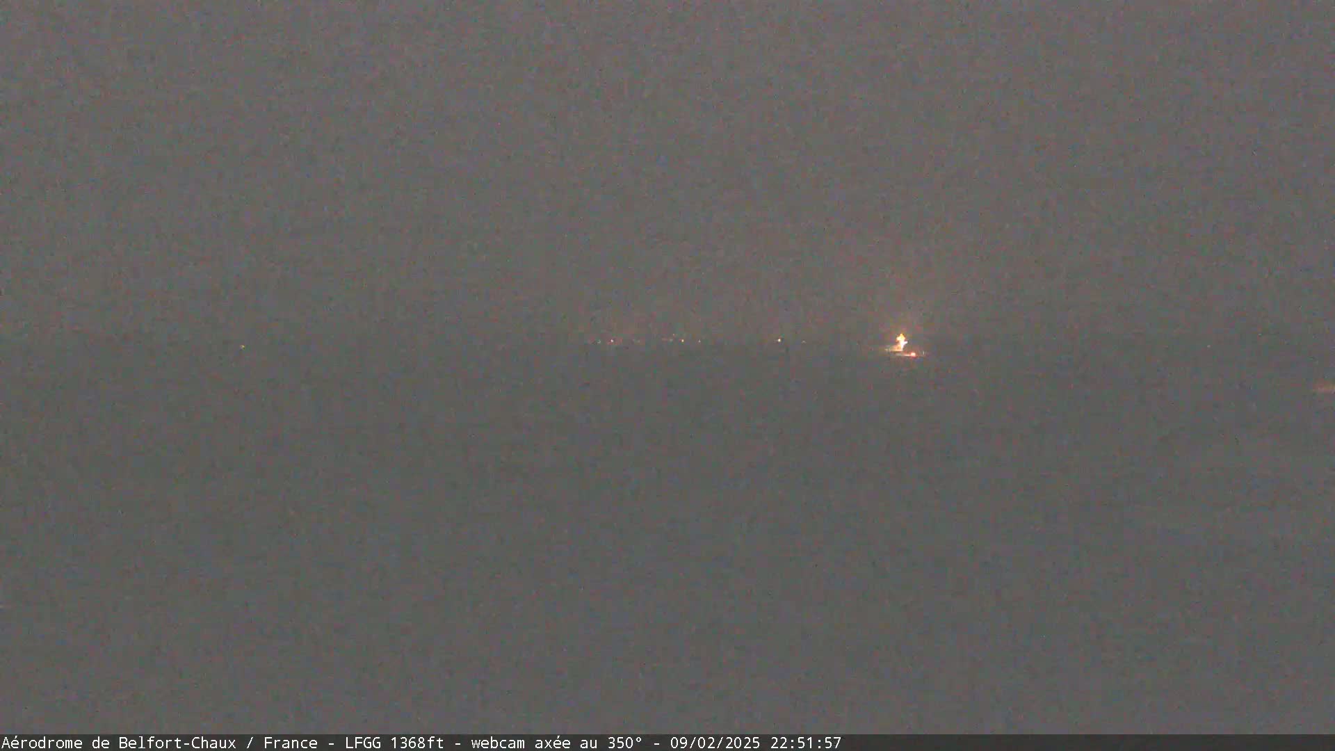 A hazy, dark night scene shows a distant line of faint lights.