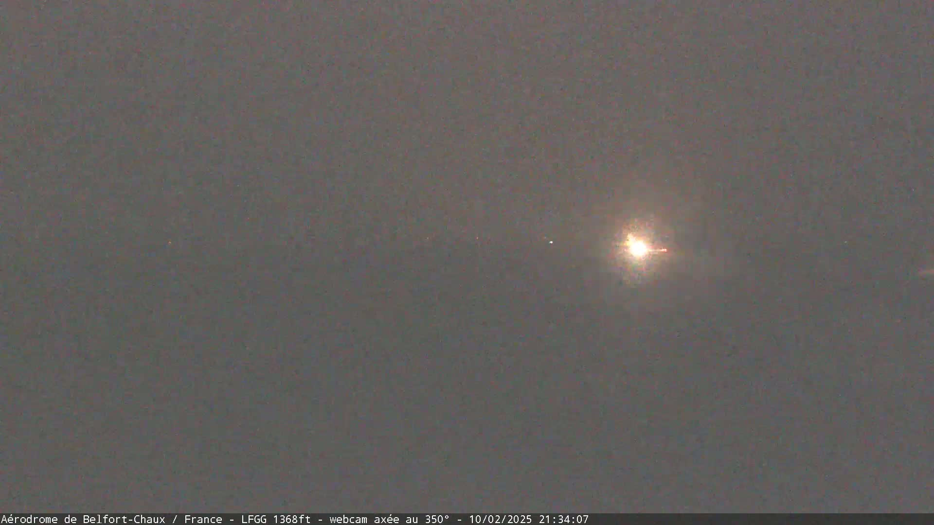 A bright light, possibly a planet or star, is visible in a dark, overcast night sky.