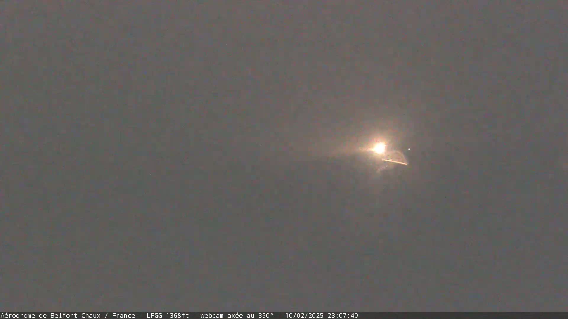 A bright streak of light, possibly a meteor, is visible in the night sky.