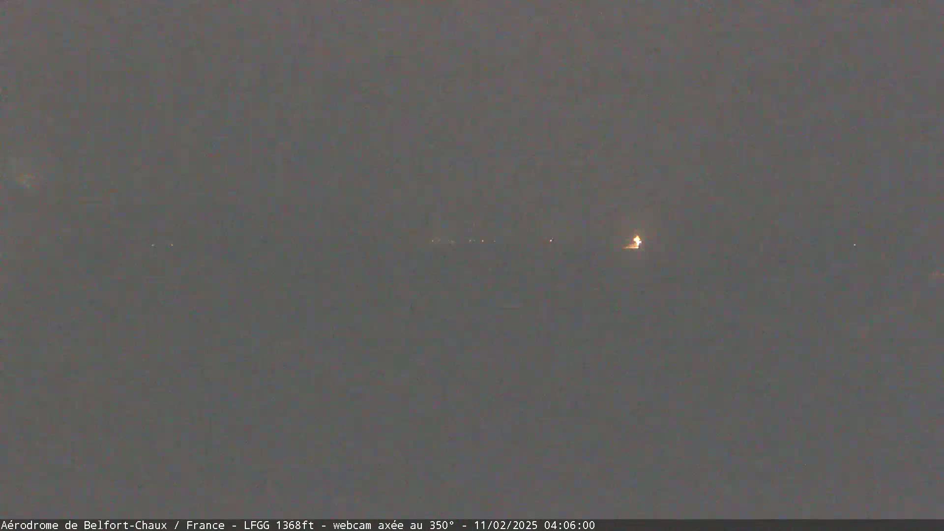 A dark, nighttime scene shows a few distant lights on the horizon under a gray sky.