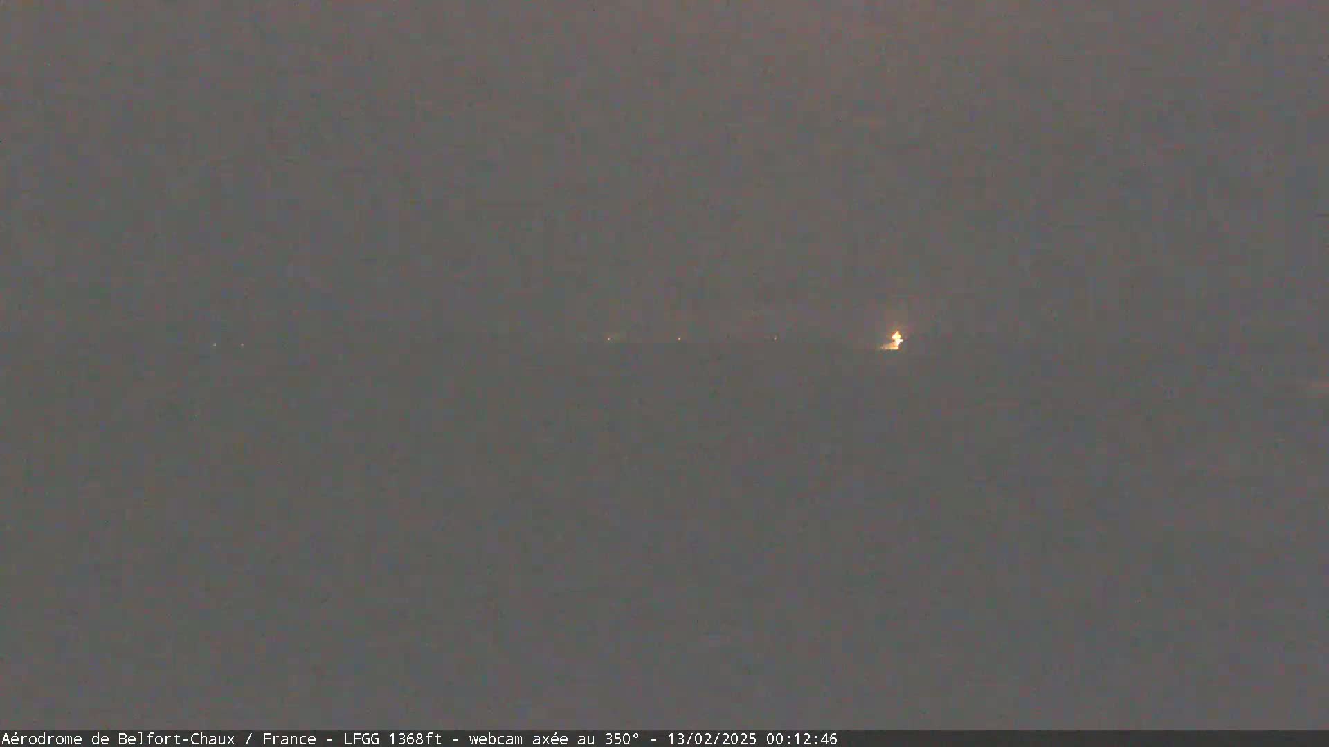 A dimly lit, hazy landscape is visible at night, with a few distant lights.
