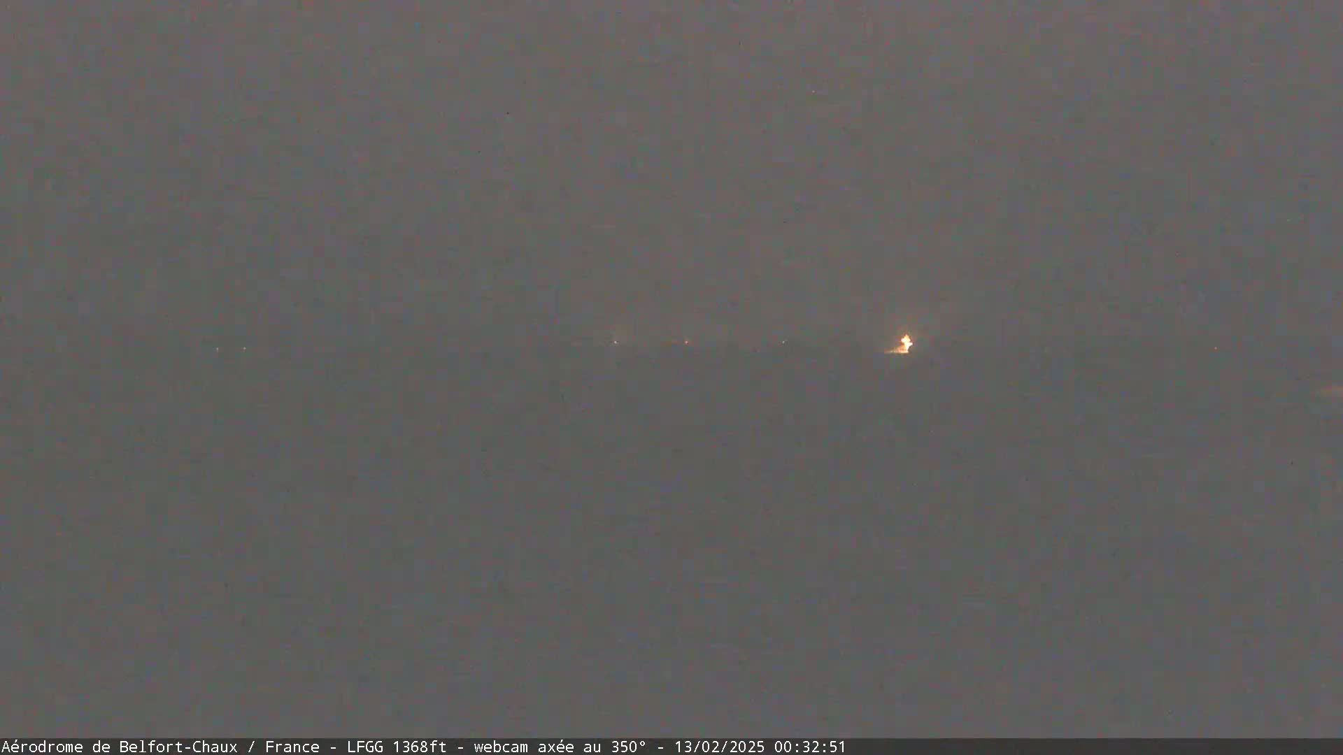 A dark, hazy nighttime scene shows a few faint lights in the distance.