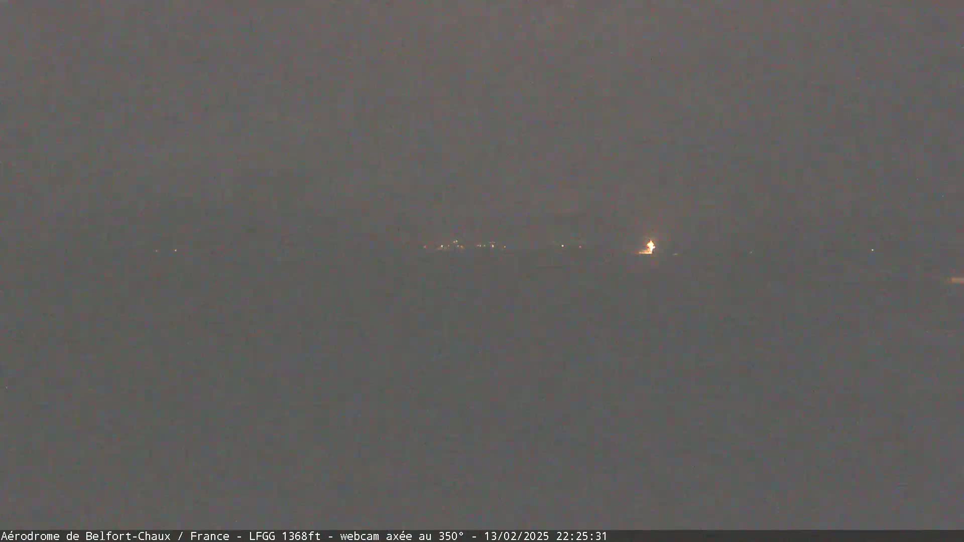 A dimly lit, nighttime landscape is visible, showing a few faint lights in the distance under a dark, overcast sky.