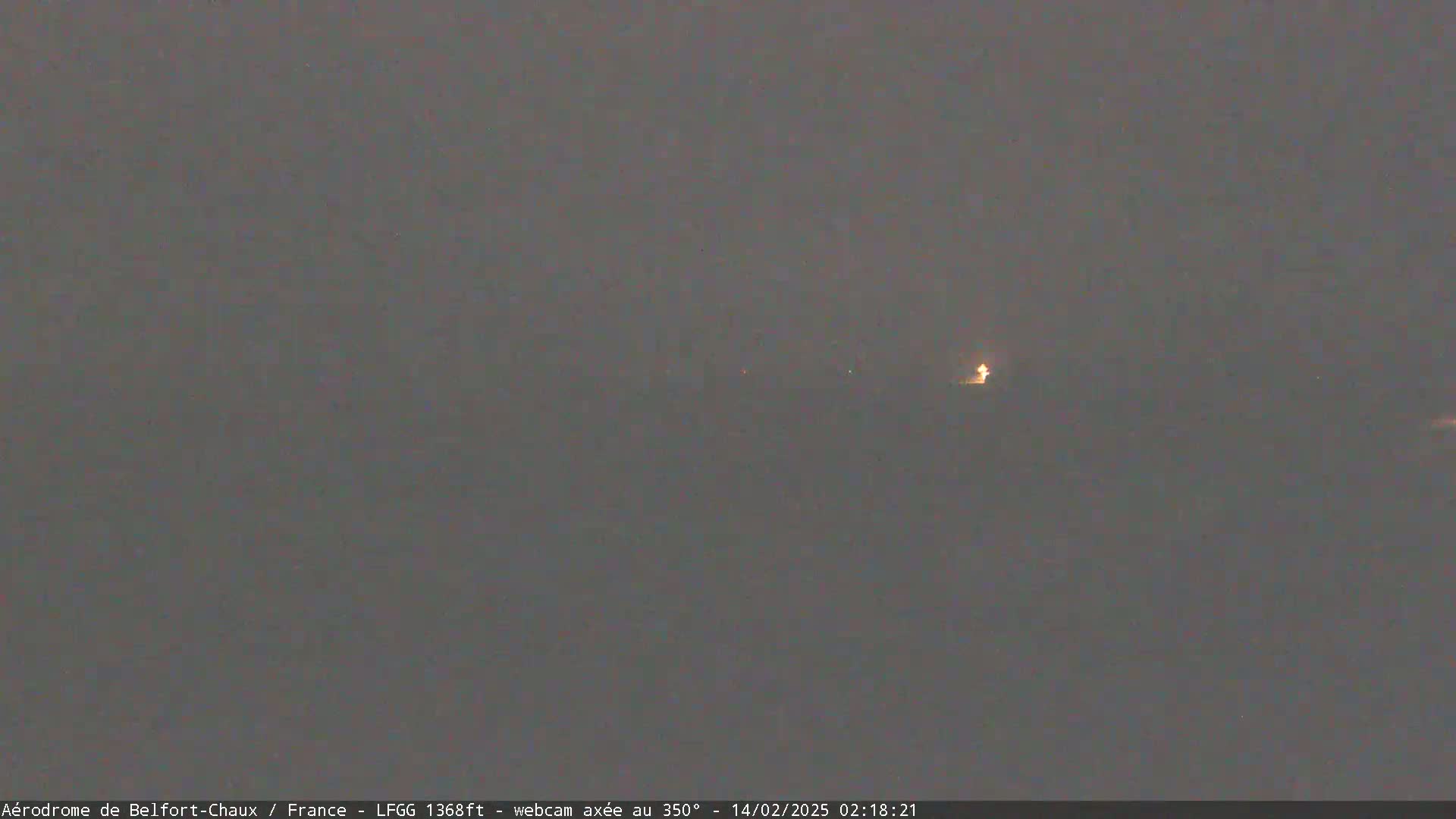 A dimly lit, hazy landscape is visible at night with a single light source in the distance.