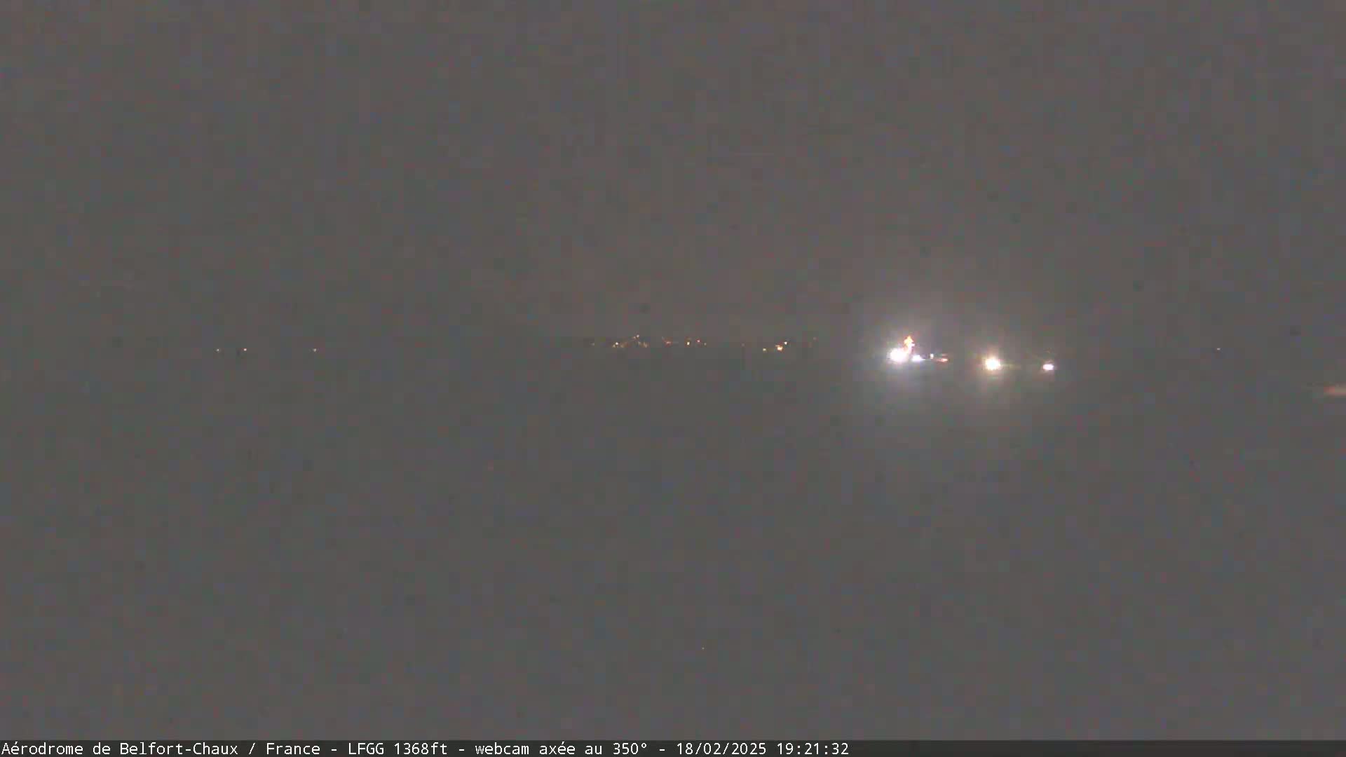 A nighttime long shot shows a few distant headlights on a dark road under a gray sky.