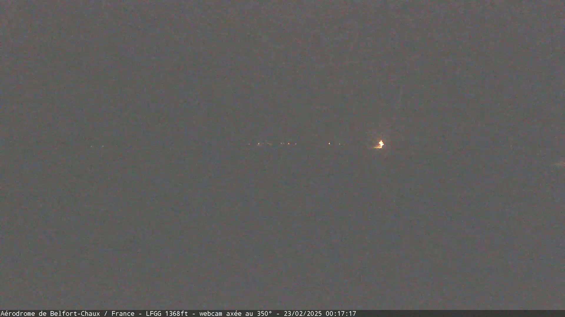 A nighttime, dimly lit landscape is visible under a dark sky.