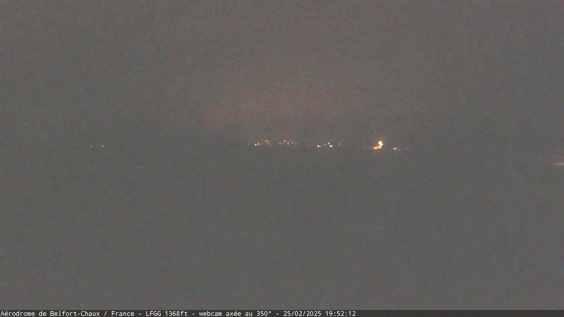 A dimly lit, distant town is visible at night under a dark, overcast sky.