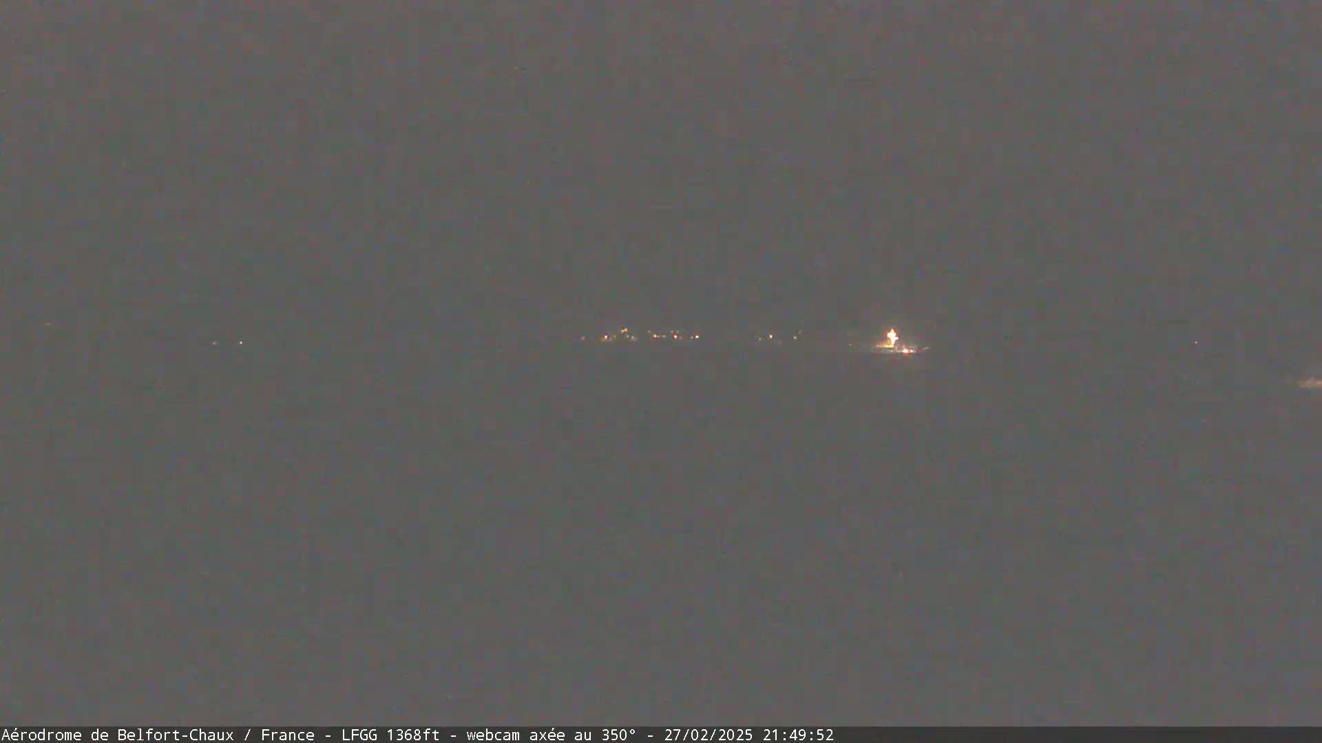 A distant line of faint lights is visible at night under a dark, overcast sky.