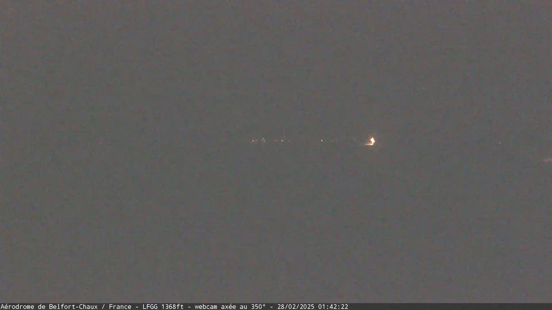 A dark, nighttime scene shows a distant line of faint lights.