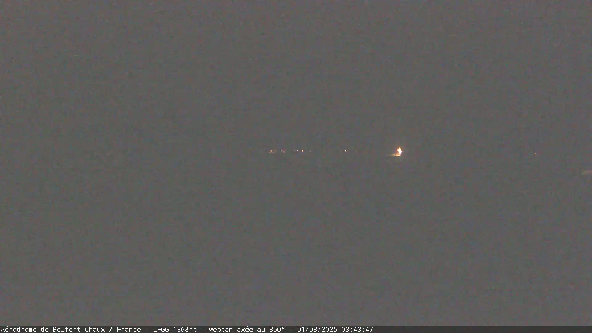 A dark, nighttime scene shows a distant line of faint lights.