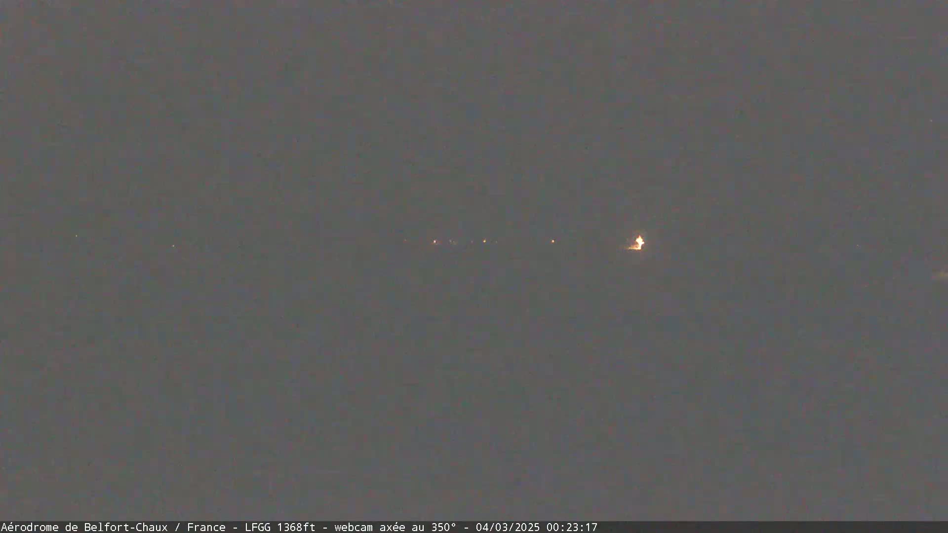 A nighttime, low-light view shows a distant line of faint lights.