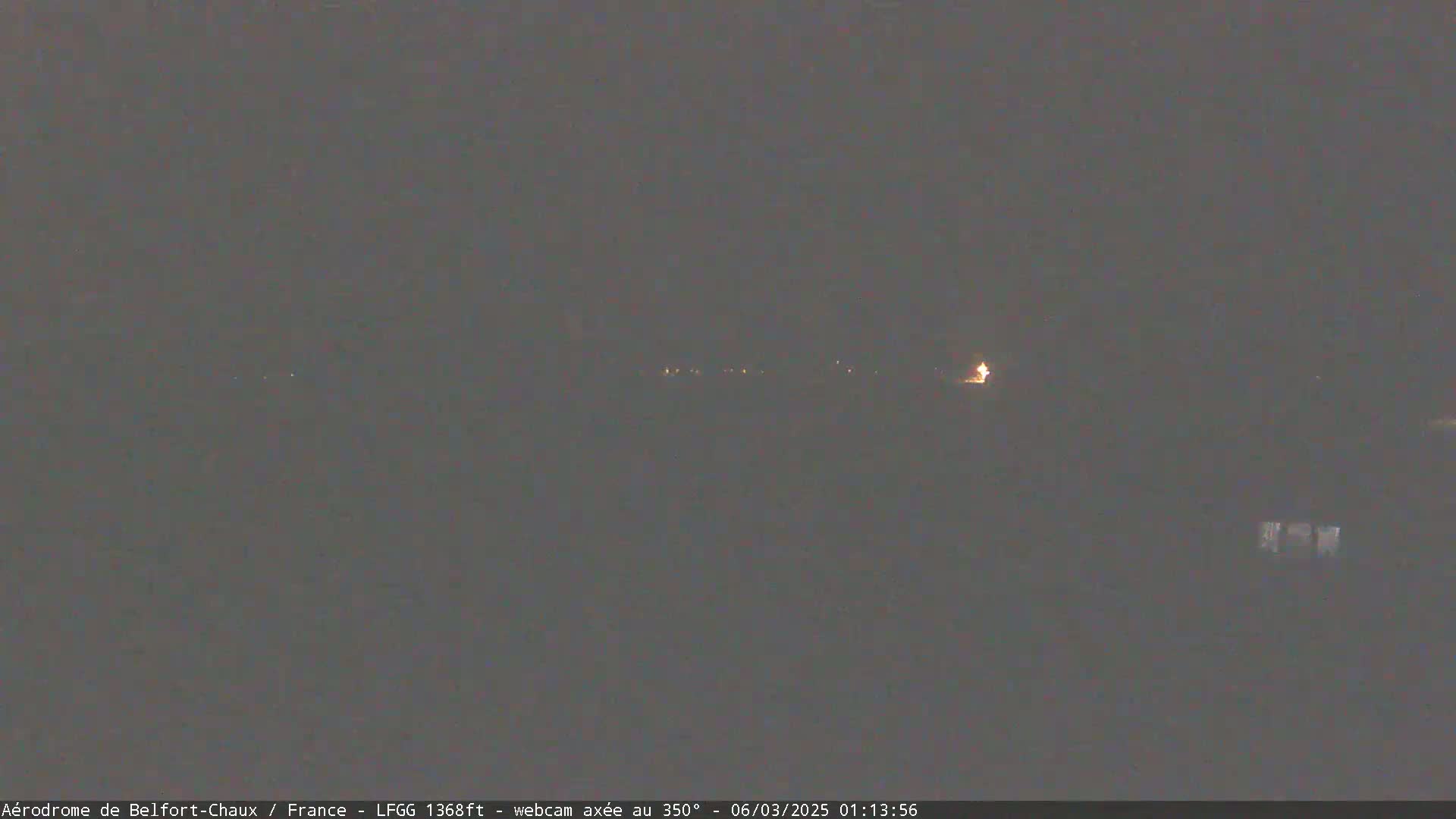 A dark, nighttime scene shows a few distant lights on the horizon.
