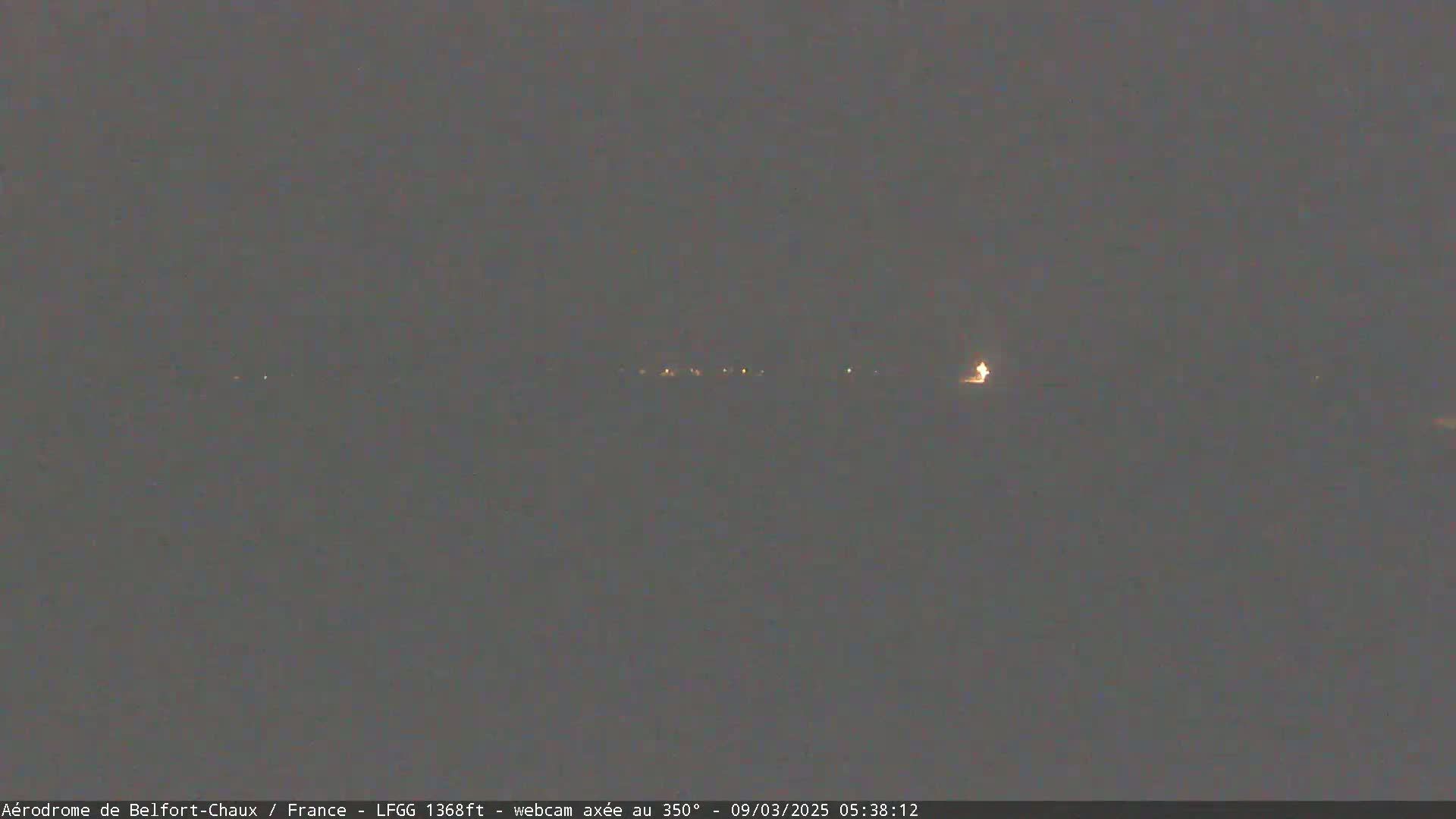A dark, hazy night scene shows a distant line of faint lights.